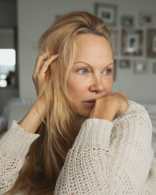 Pamela Anderson apoya la barbilla en las manos en un retrato contemplativo y sin maquillaje, vestida con un cómodo jersey de punto abierto color crema. Mientras se pasa suavemente la mano por su melena rubia suelta, con una pared de fotos familiares ligeramente desenfocada de fondo, muestra esa confianza tranquila y esa belleza auténtica que definen su etapa en Arcady. Acompañó este primer plano tan íntimo con un reflexivo mensaje: "Mientras sigamos aprendiendo, vamos por el buen camino… 🤍✨". | Fuente: Instagram/pamelaanderson