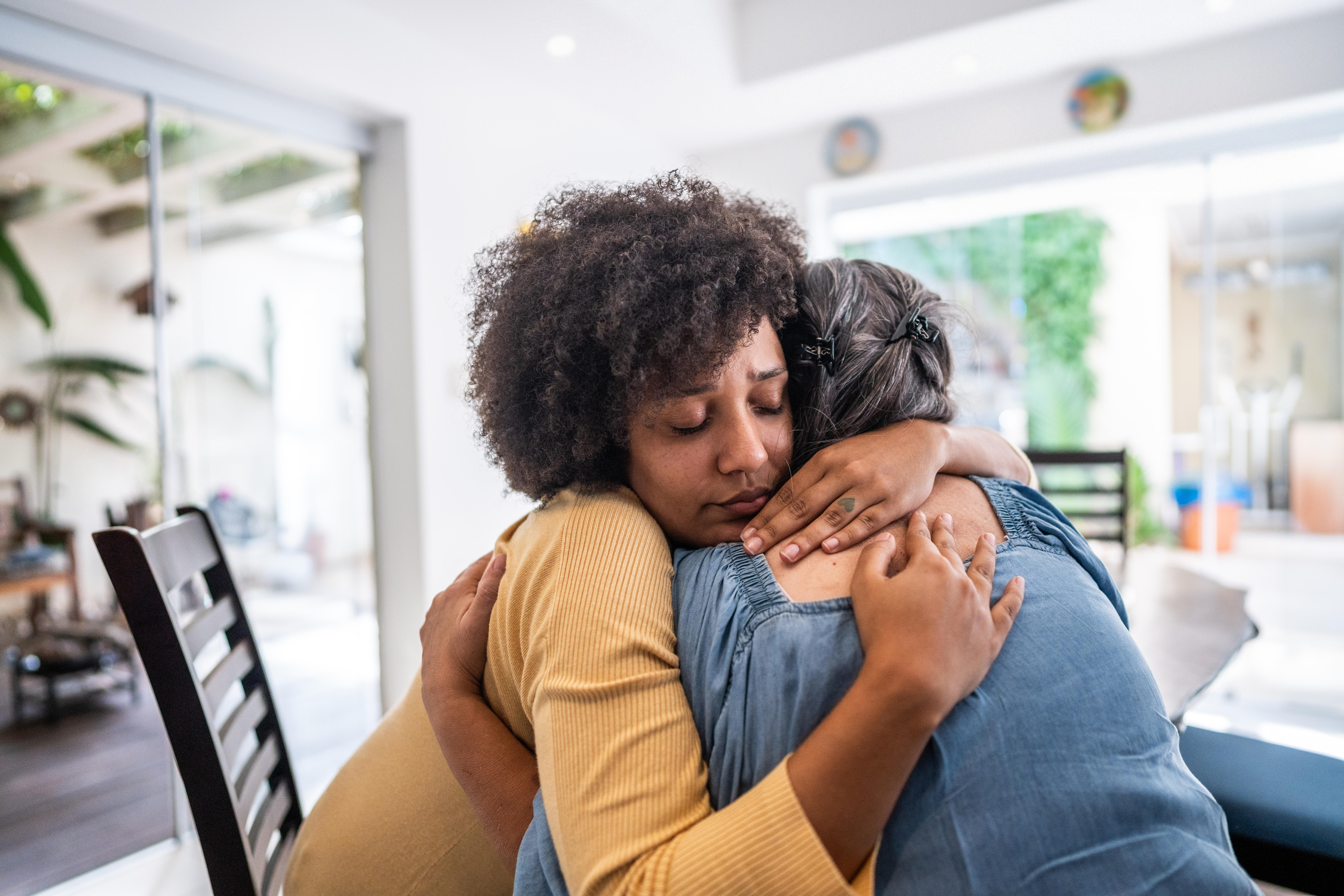 Joven triste abrazando a su madre en casa | Foto: Getty Images
