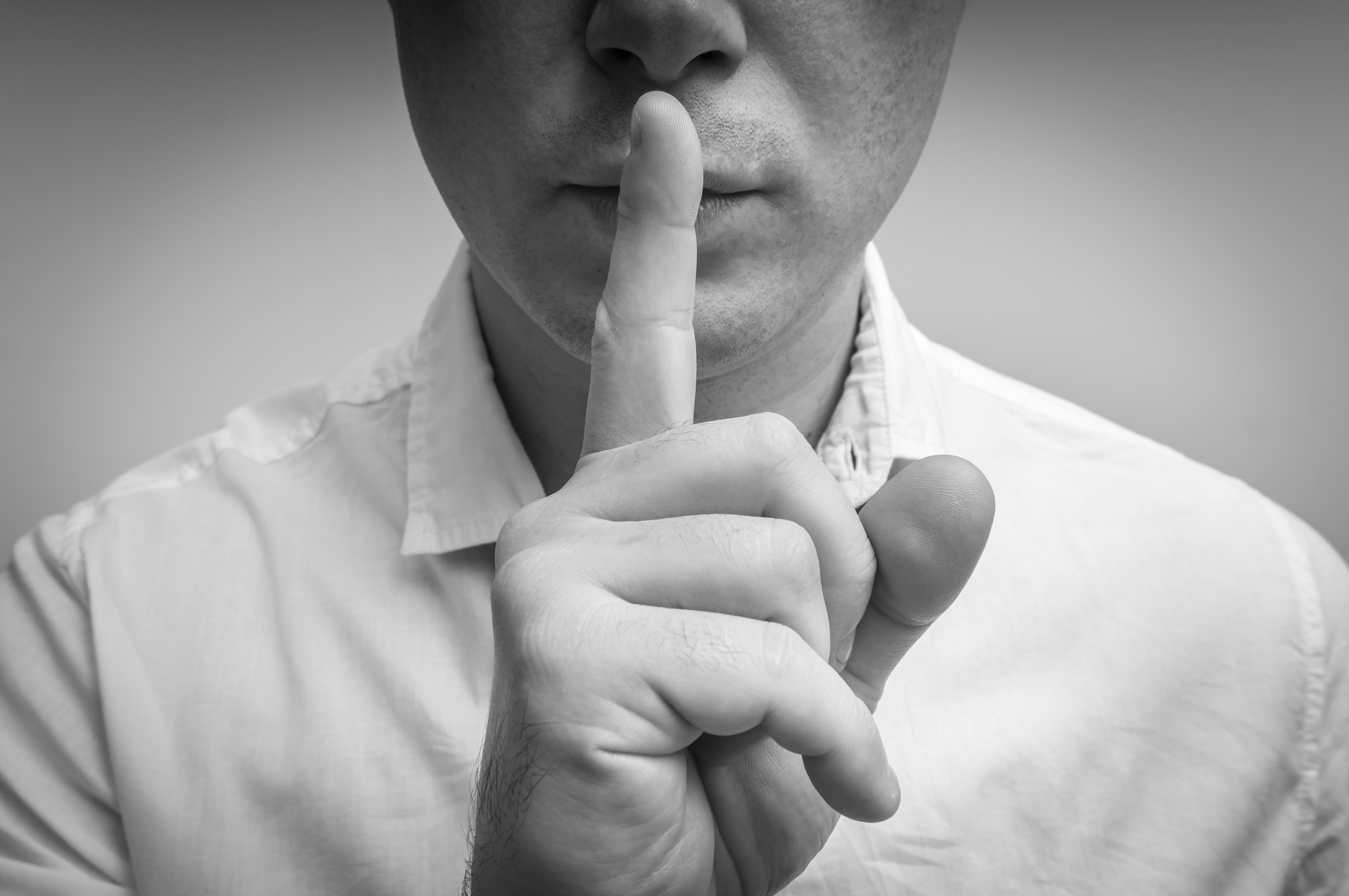 Un hombre con el dedo en los labios | Fuente: Shutterstock