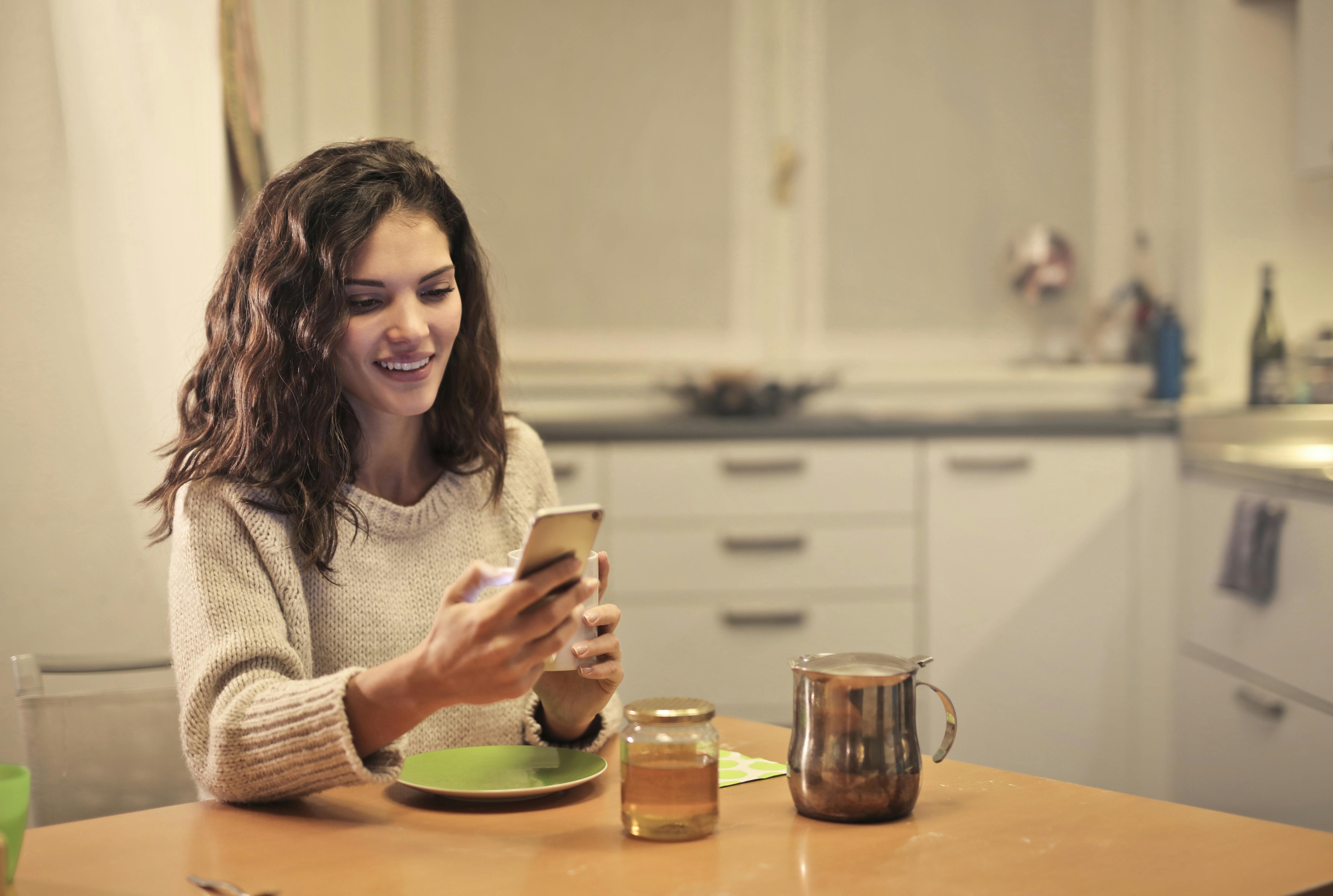 Una mujer feliz mirando su teléfono | Fuente: Pexels