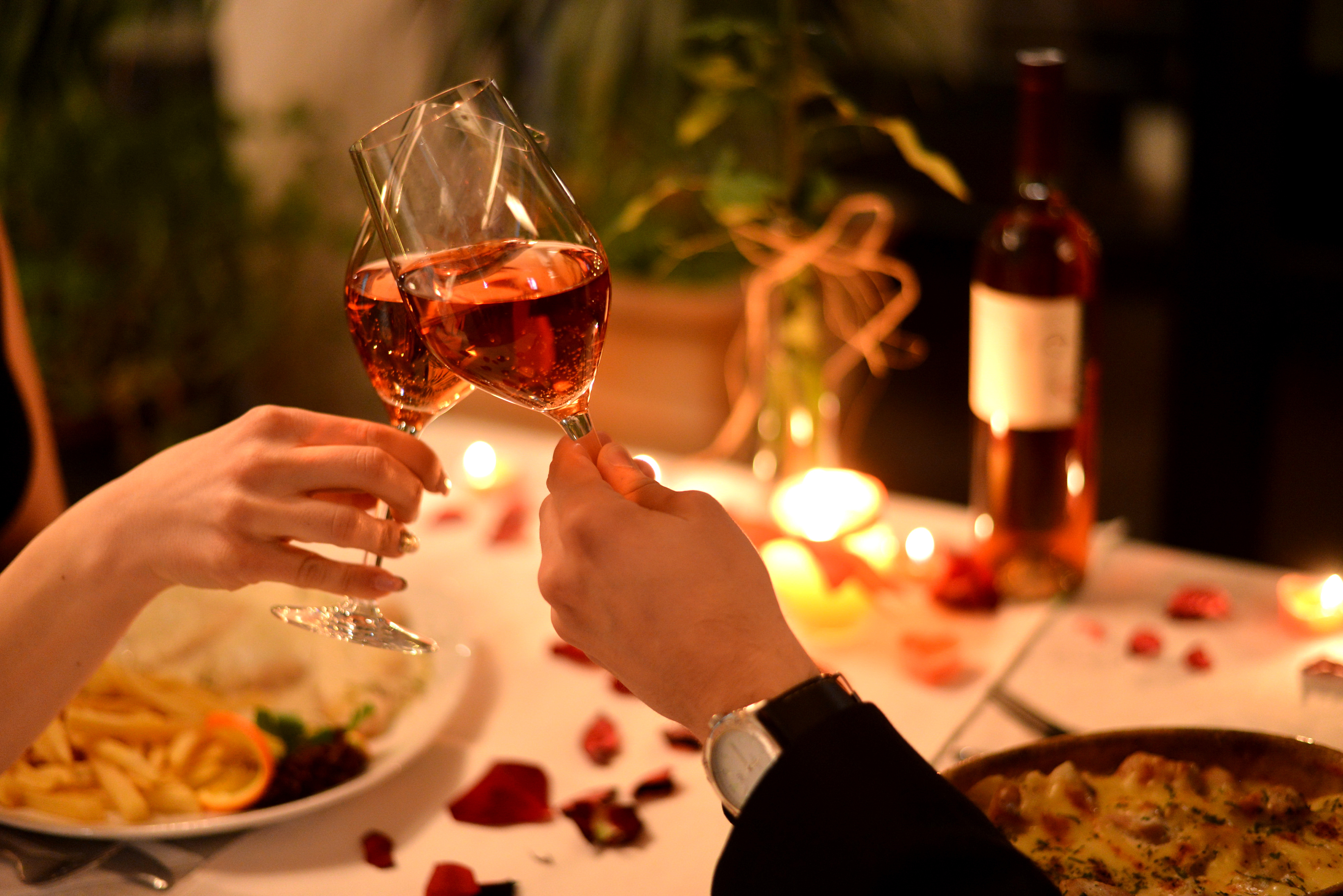 Una pareja chocando copas de vino durante una cena romántica | Fuente: Shutterstock