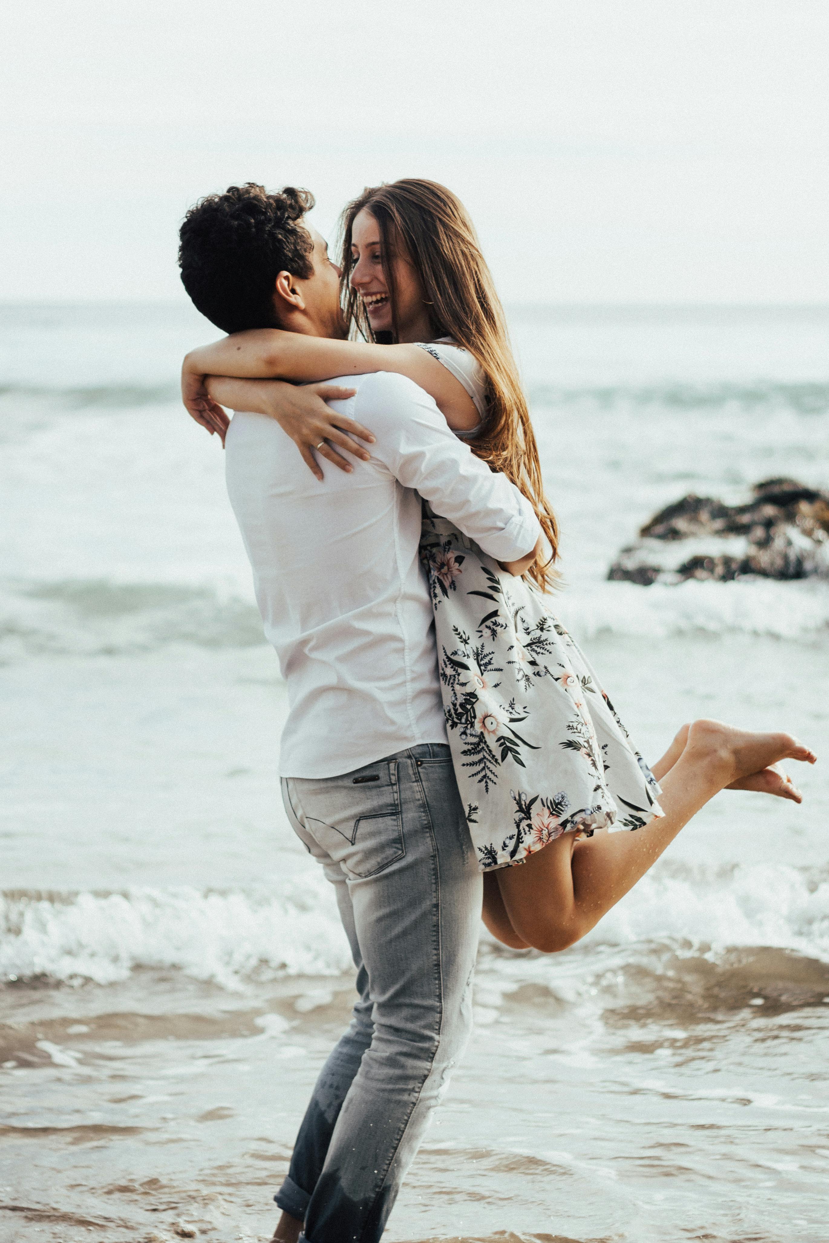 Pareja feliz abrazándose en la playa | Fuente: Pexels