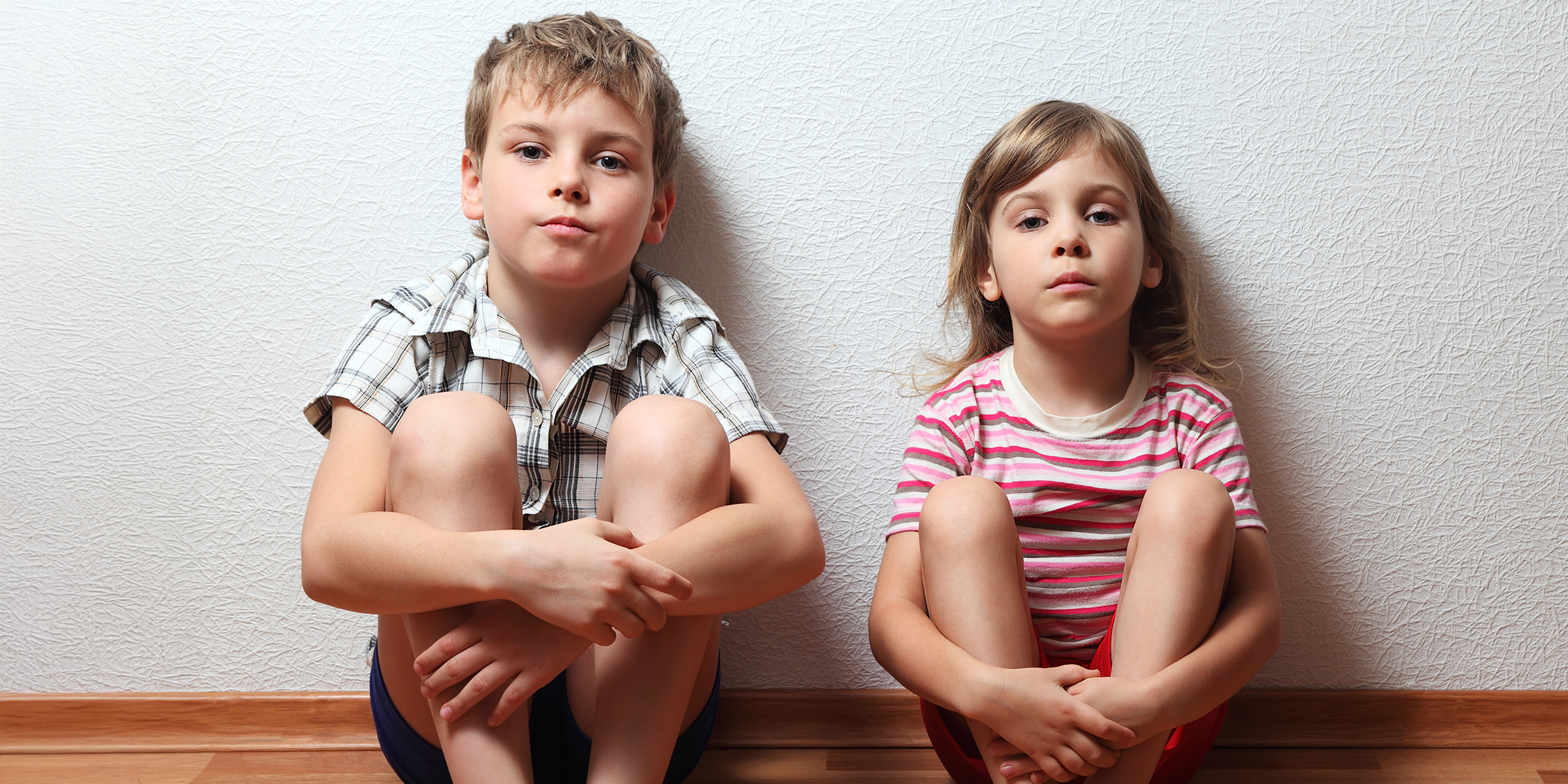 Un niño y una niña sentados en el suelo | Fuente: Shutterstock