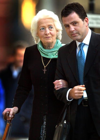 Frances Shand Kydd, la madre de la fallecida Diana, Princesa de Gales, recibiendo ayuda de un hombre no identificado, el 24 de octubre de 2002 en Londres. | Imagen: Getty Images