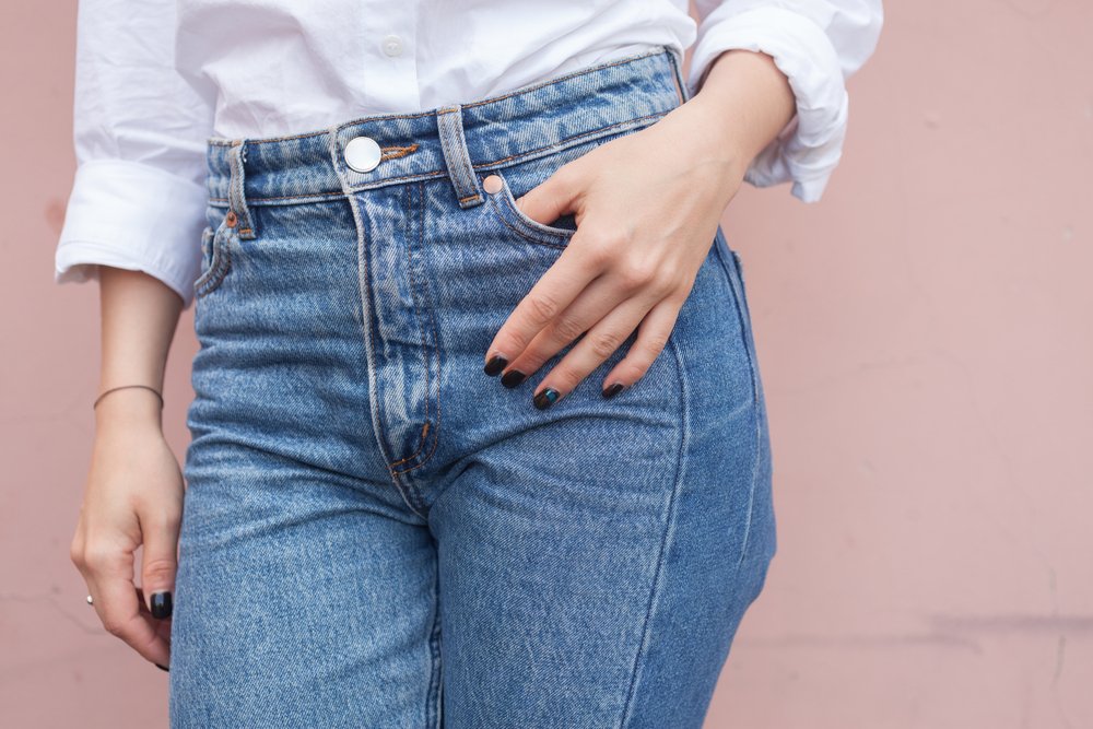 Mujer vistiendo pantalones de jean con camisa blanca de mangas largas. | Foto: Shutterstock