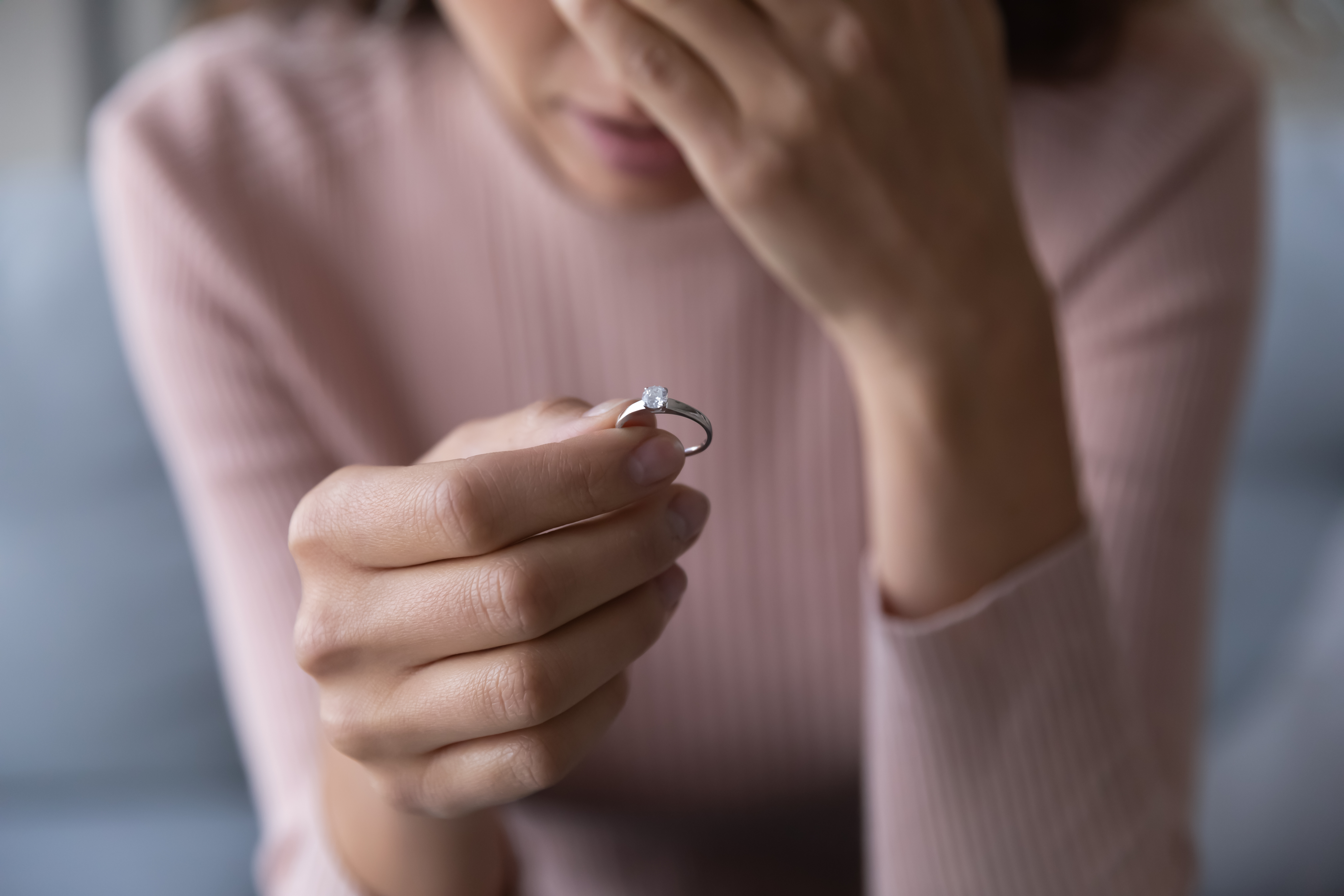 Una mujer triste sujetando un anillo | Fuente: Shutterstock