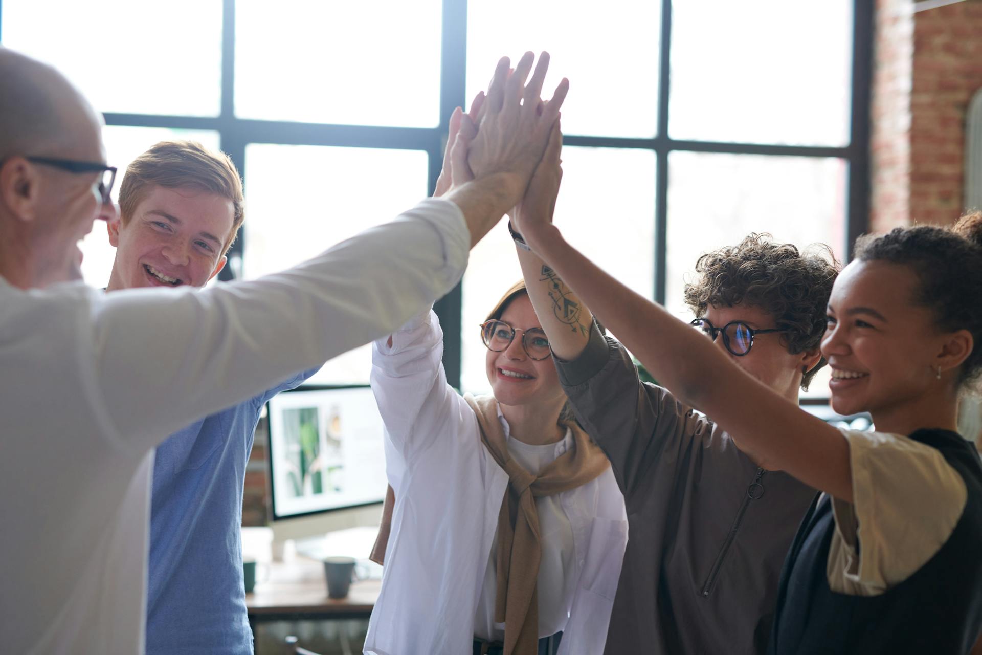 Una foto que muestra a unos empleados haciendo un huddle con su jefe | Fuente: Pexels