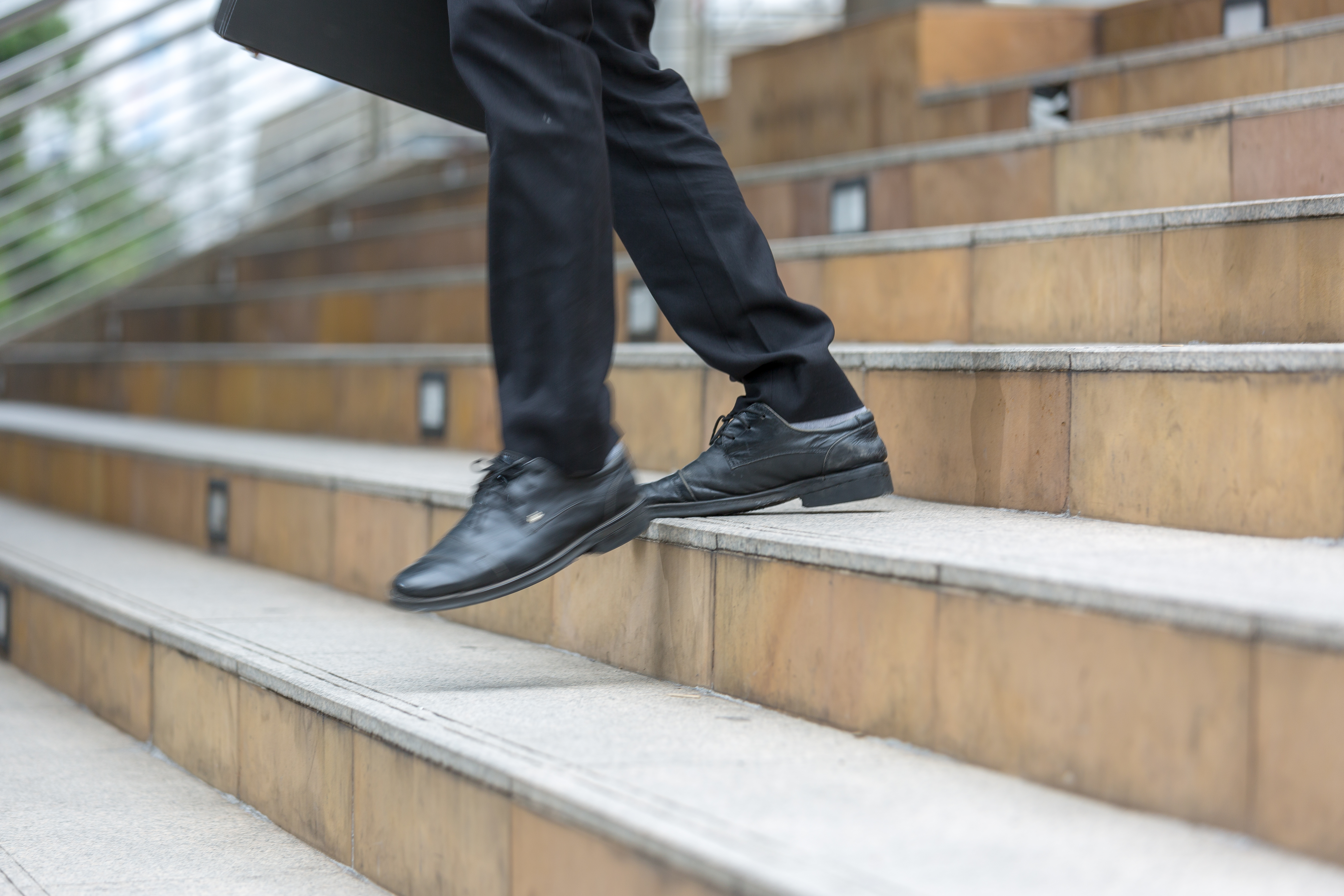 Una persona de negocios baja por la escalera con prisa. | Fuente: Shutterstock
