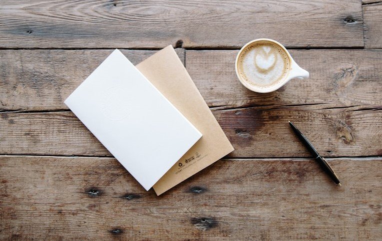 Sobres, bolígrafo y una taza con café. | Foto: Unsplash