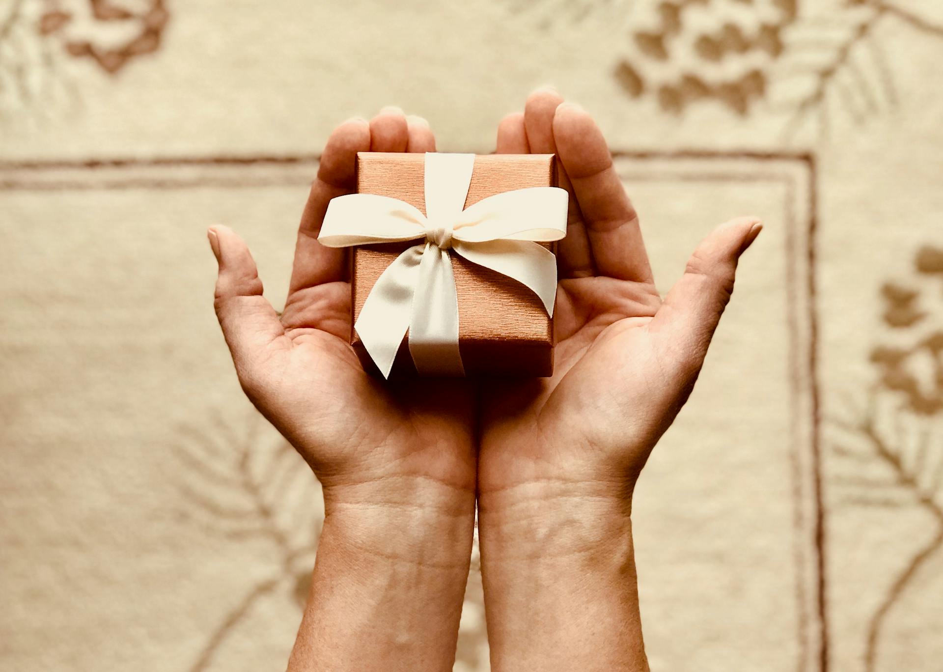 Primer plano de una mujer sosteniendo una pequeña caja de regalo marrón | Fuente: Pexels