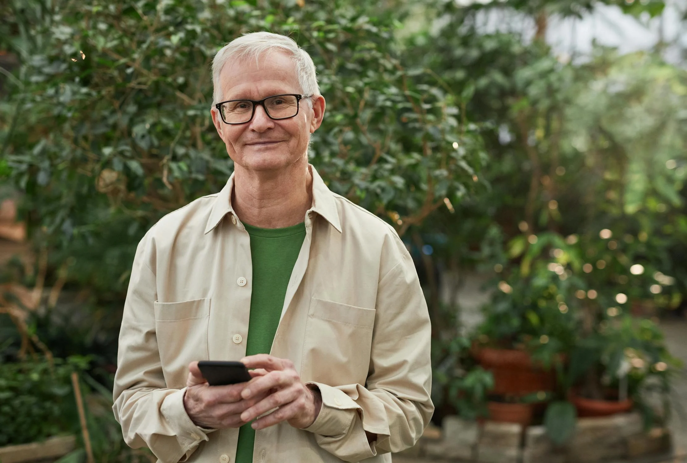 Un hombre sonriente sosteniendo su teléfono ⏐ Fuente: Pexels