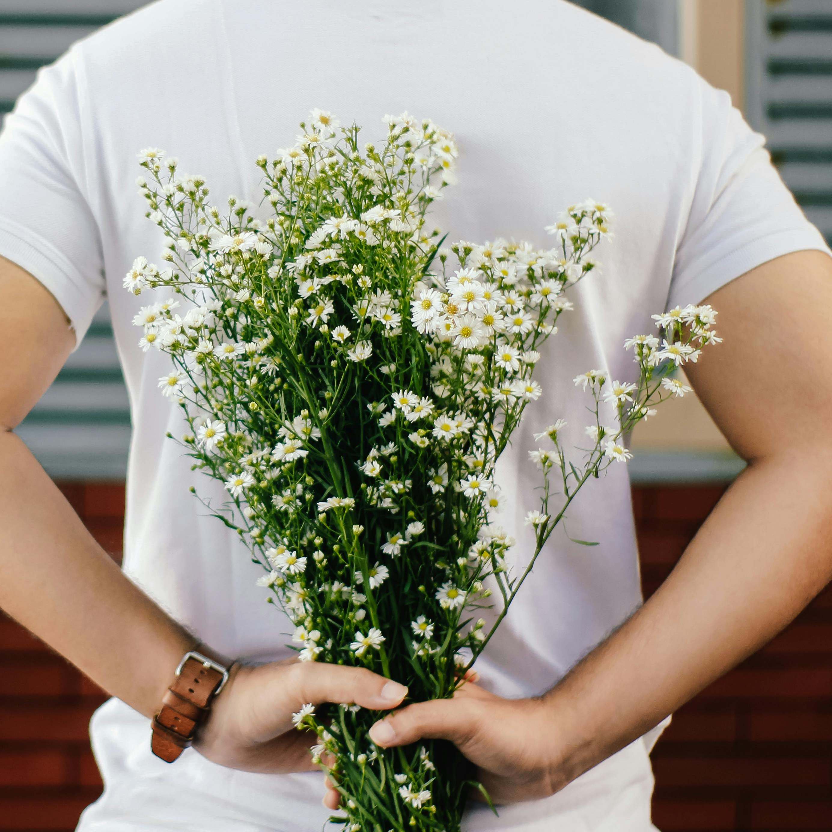 Un hombre con un ramo de flores a la espalda | Fuente: Pexels