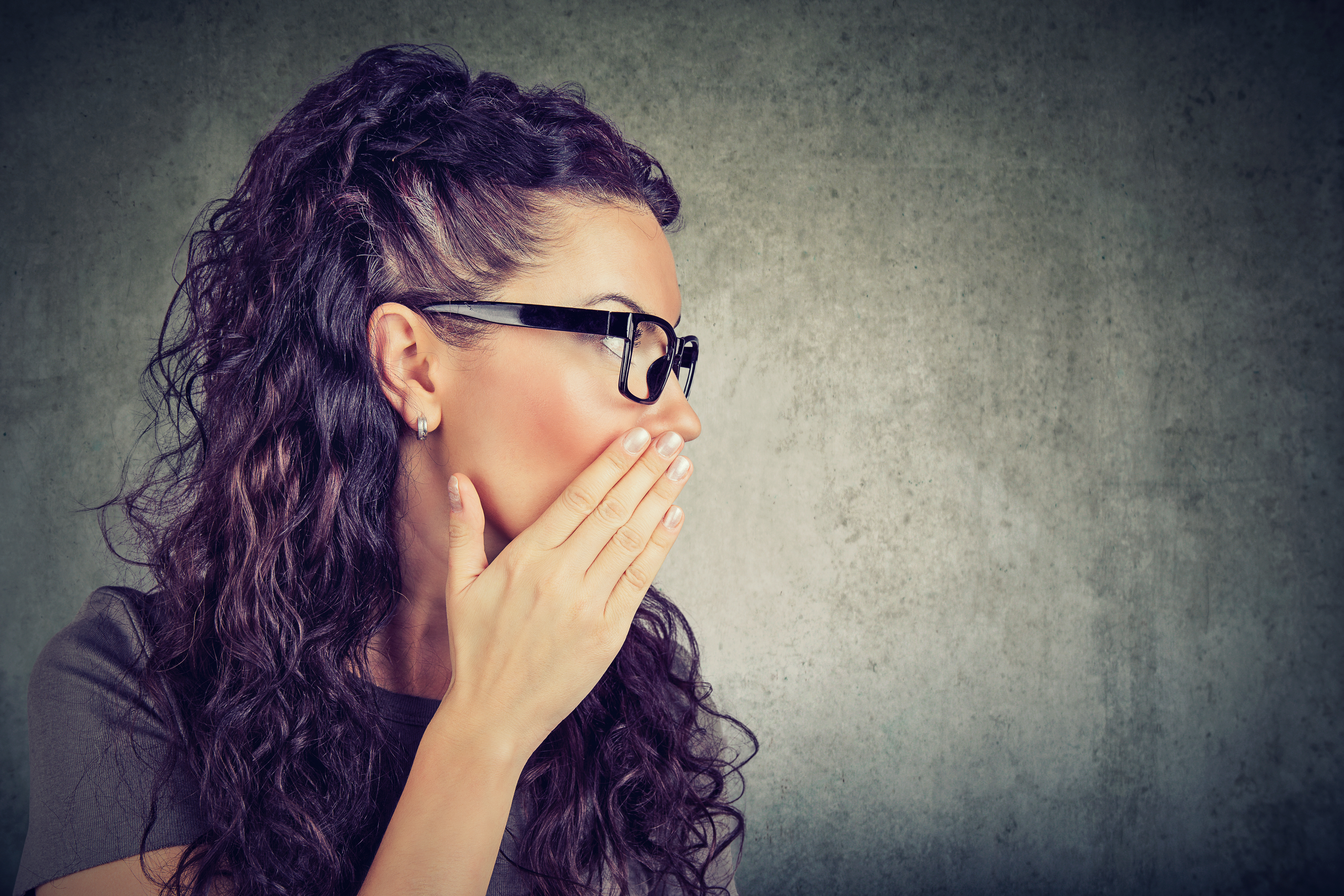 Una mujer tapándose la boca con la mano | Fuente: Shutterstock