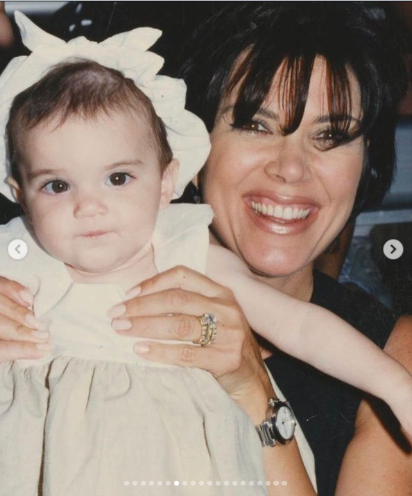Una joven Kris Jenner sostiene en brazos a la pequeña Kendall Jenner, y ambas posan muy juntas para una foto familiar. Kris lleva el pelo corto y con mucho volumen, con flequillo, mientras que Kendall lleva un vestido de color claro y un gran lazo blanco. | Fuente: Instagram/krisjenner