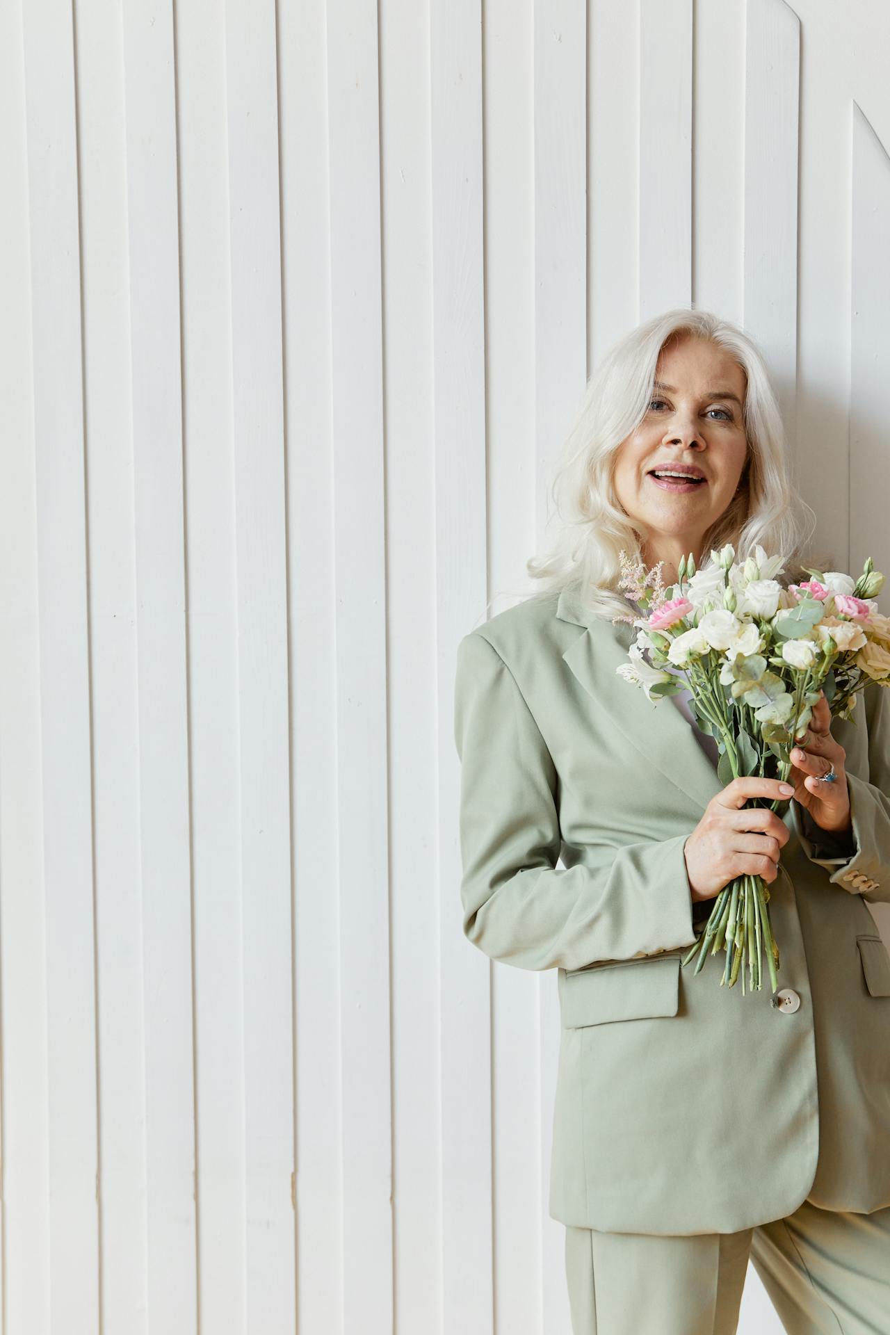 Una mujer mayor sonriente con un ramo de flores | Fuente: Pexels