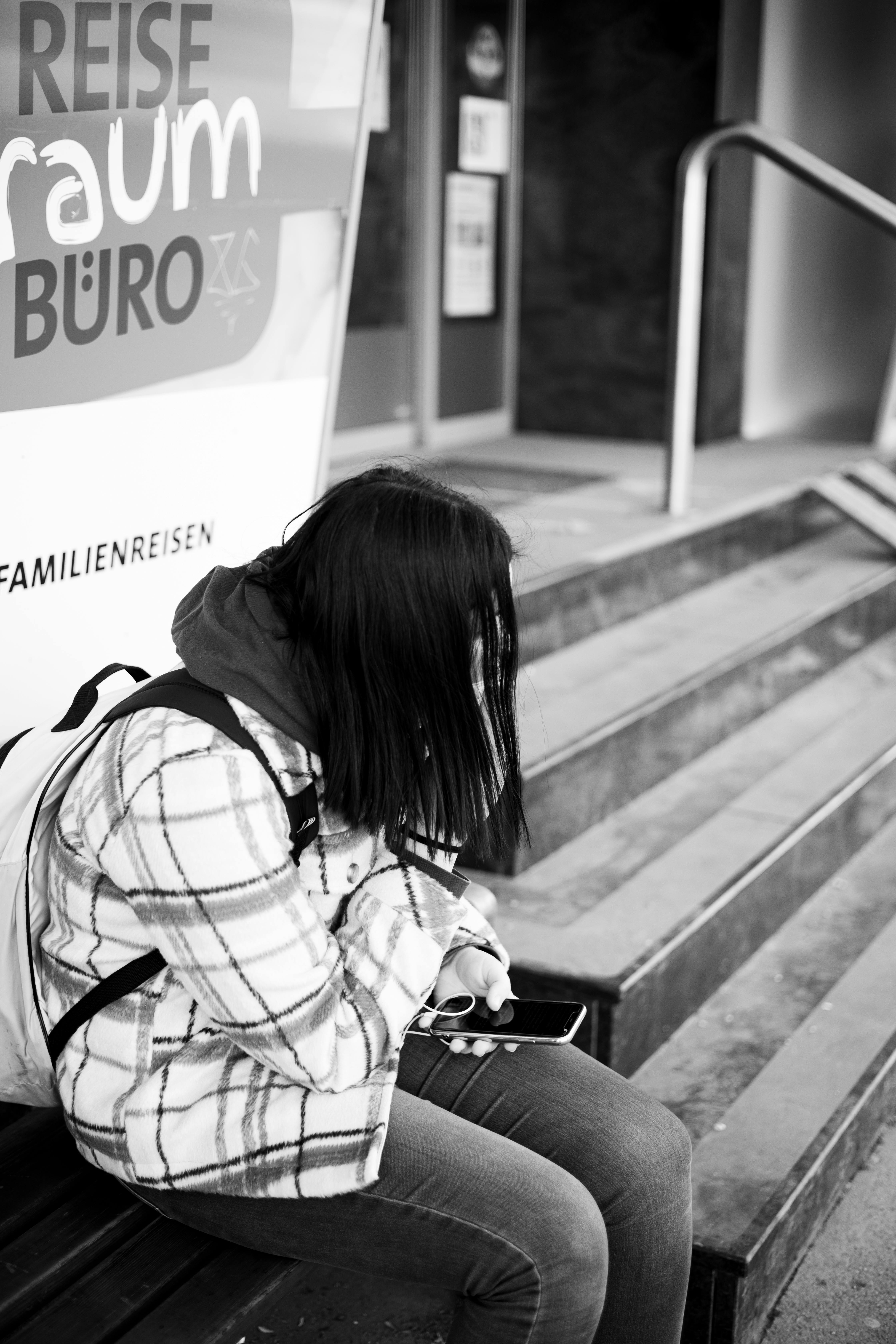 Una ragazza seduta su una panchina con il cellulare in mano | Fonte: Pexels