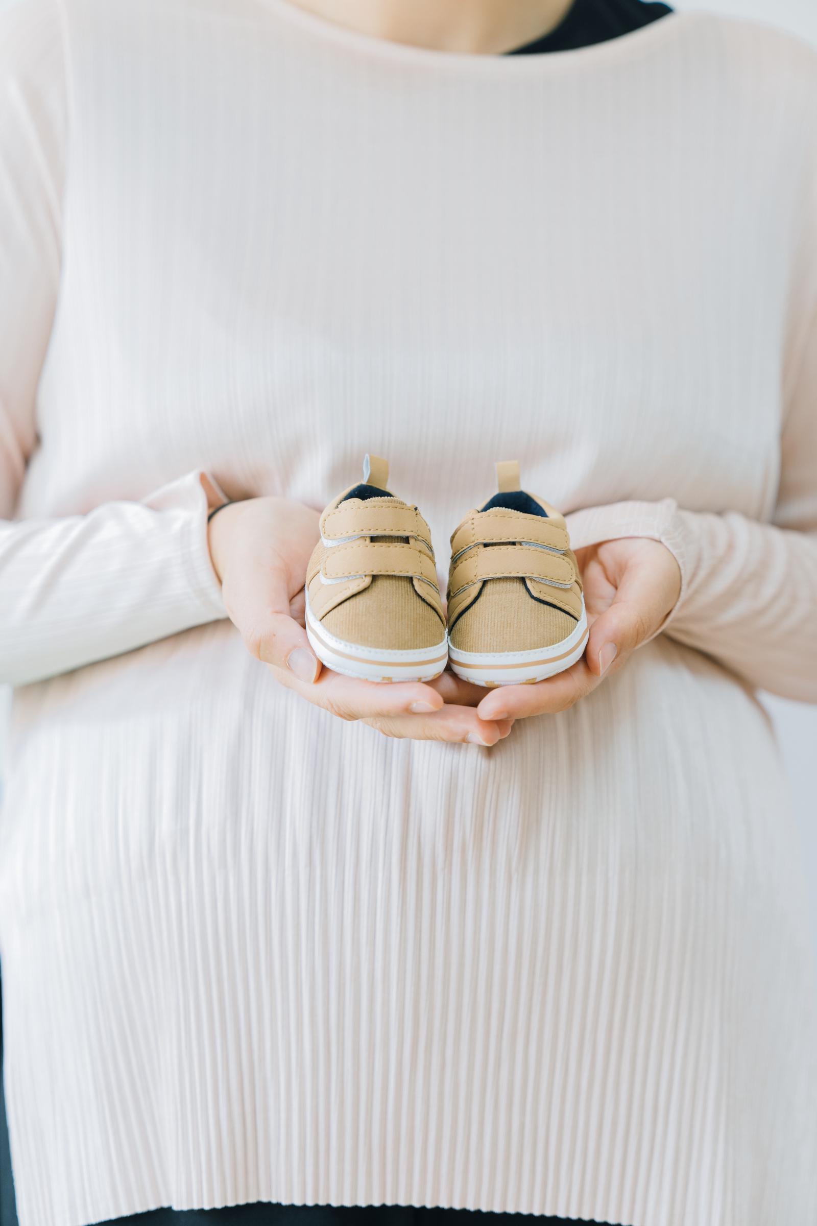 Una mujer sujetando unos zapatitos de bebé | Fuente: Freepik