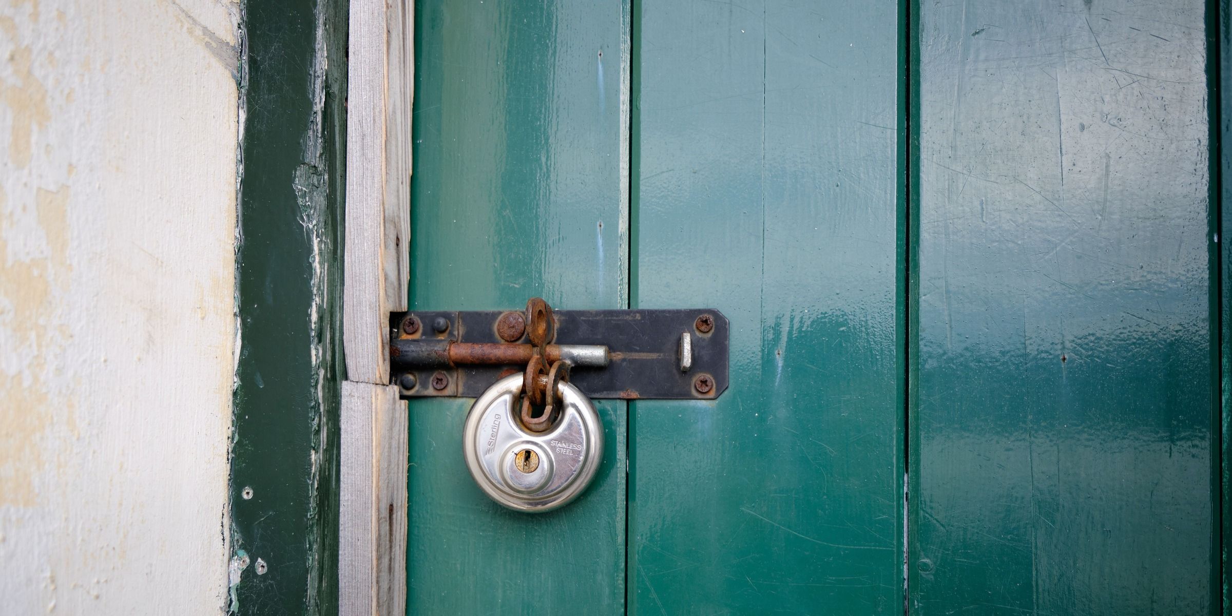 Una porta di legno verde chiusa a chiave | Fonte: Pexels