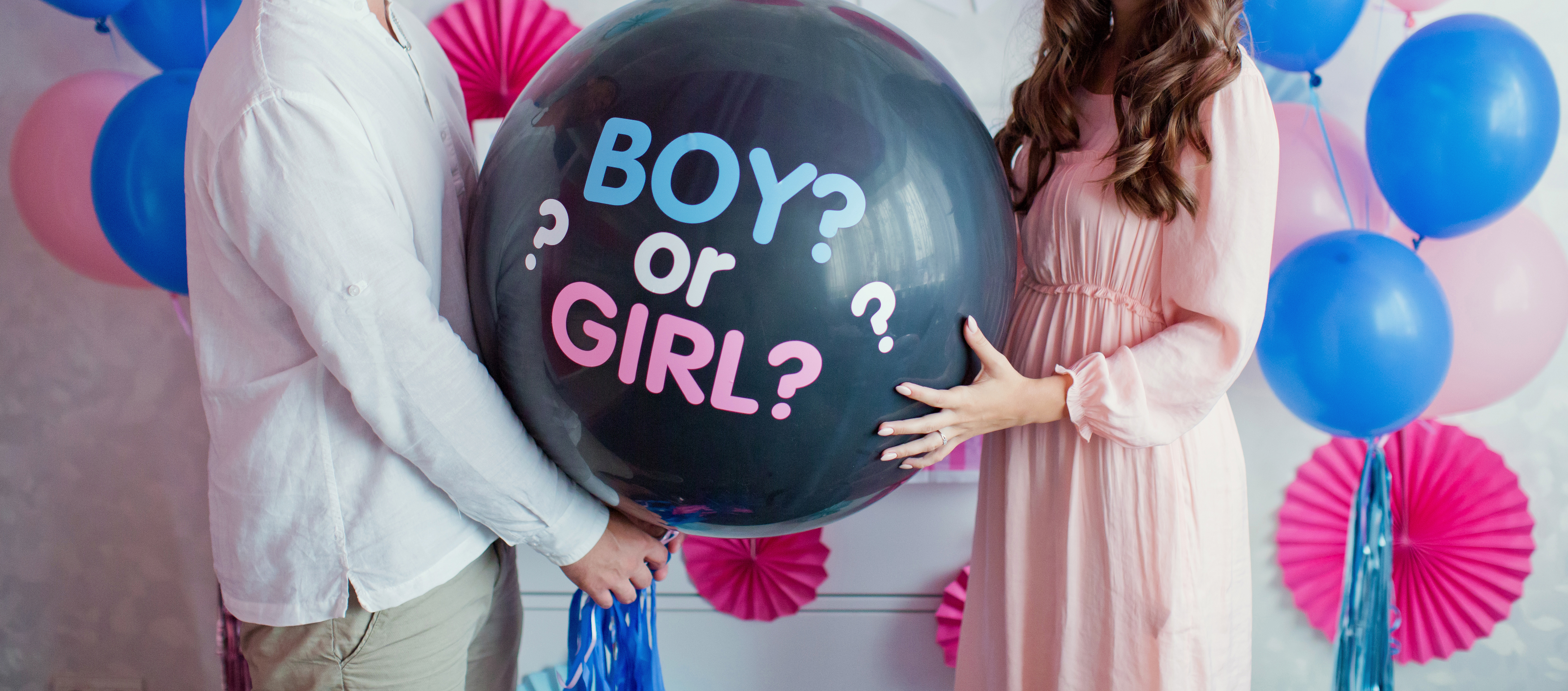 Hombre y mujer sujetando un globo negro con la inscripción "¿niño o niña?" durante una fiesta de revelación de género | Foto: Shutterstock