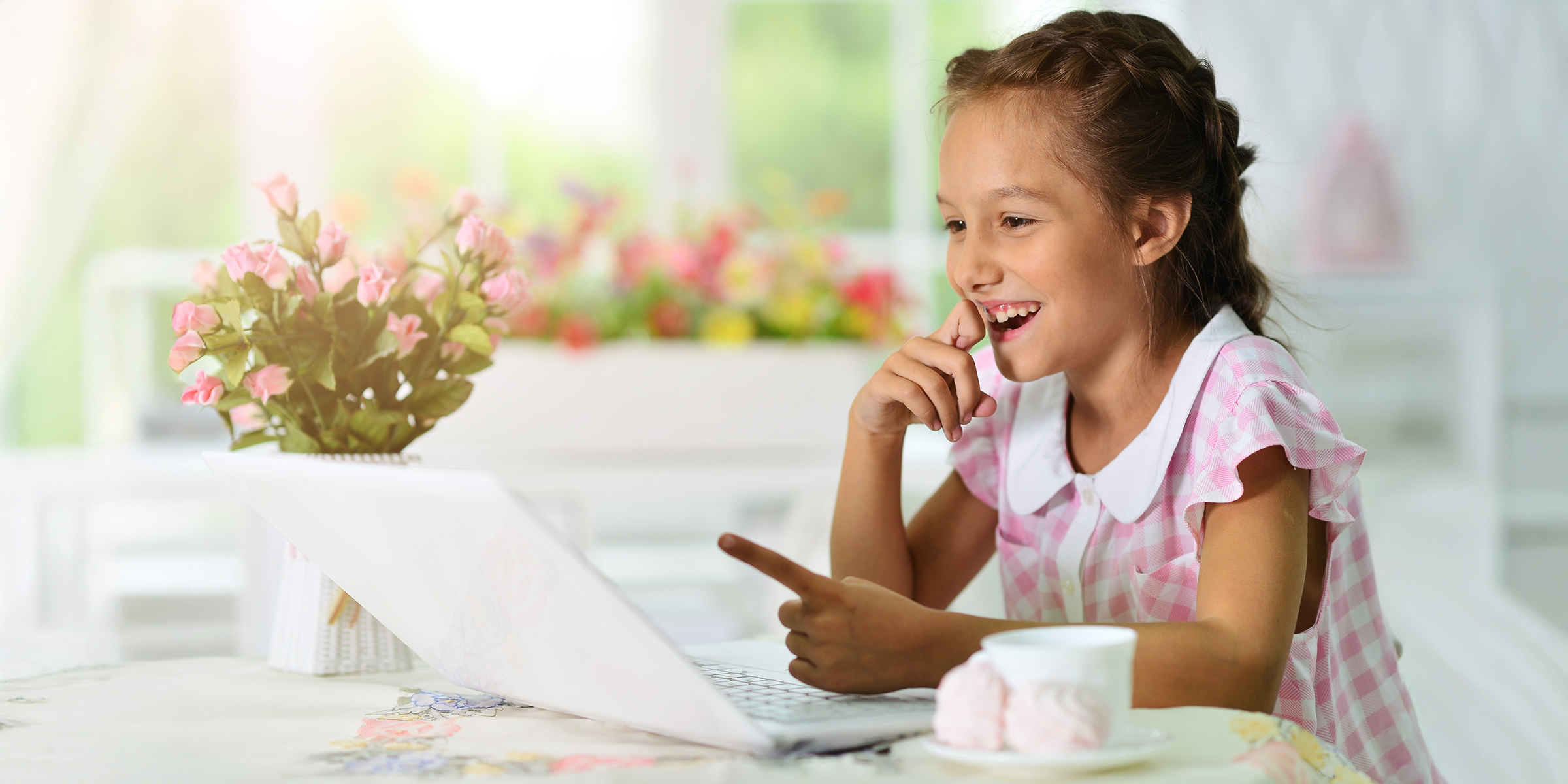 Una chica sonriente señalando la pantalla de un portátil | Fuente: Shutterstock