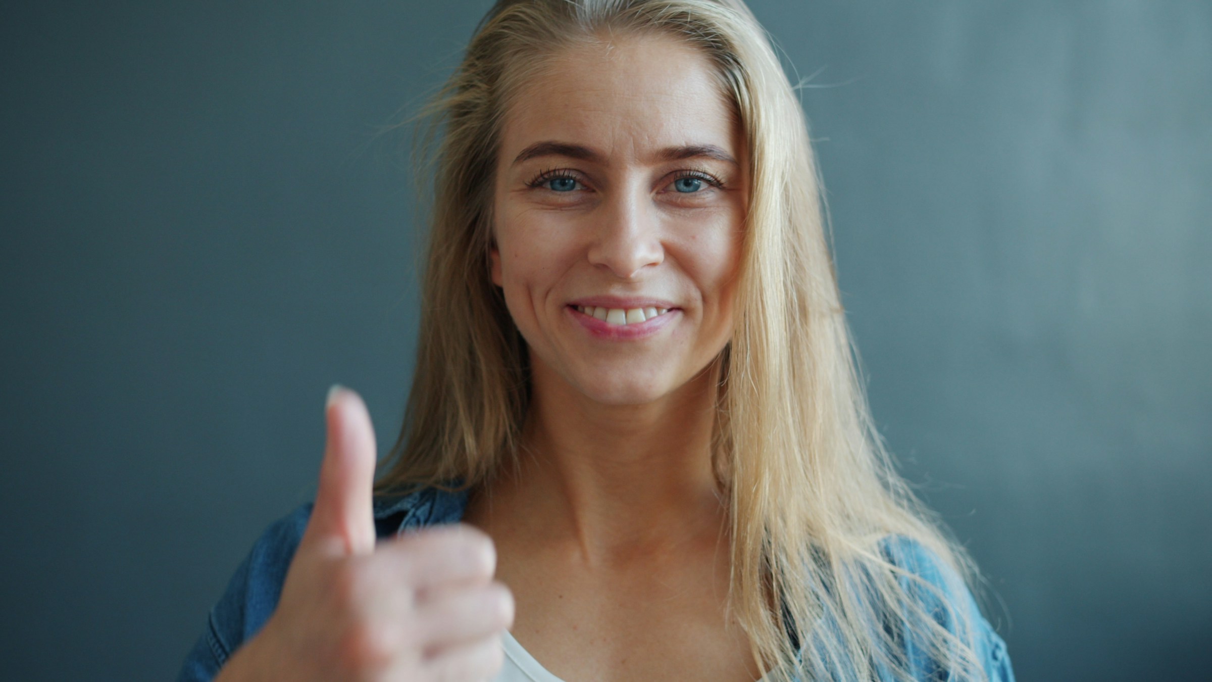 Una donna sorridente che mostra un segno di pollice in su | Fonte: Unsplash