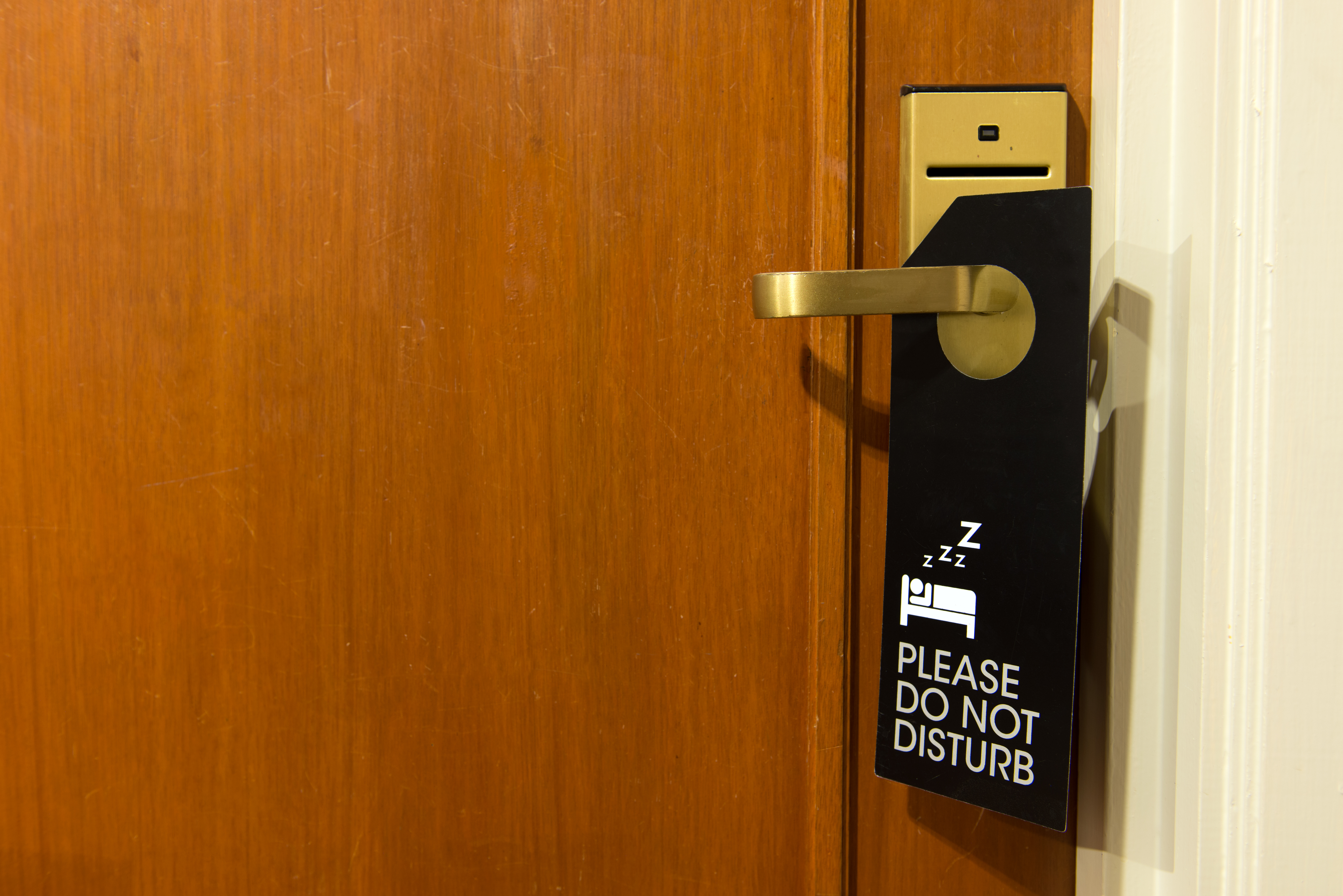 Cartel de no molestar colgado del pomo de la puerta. | Fuente: Shutterstock
