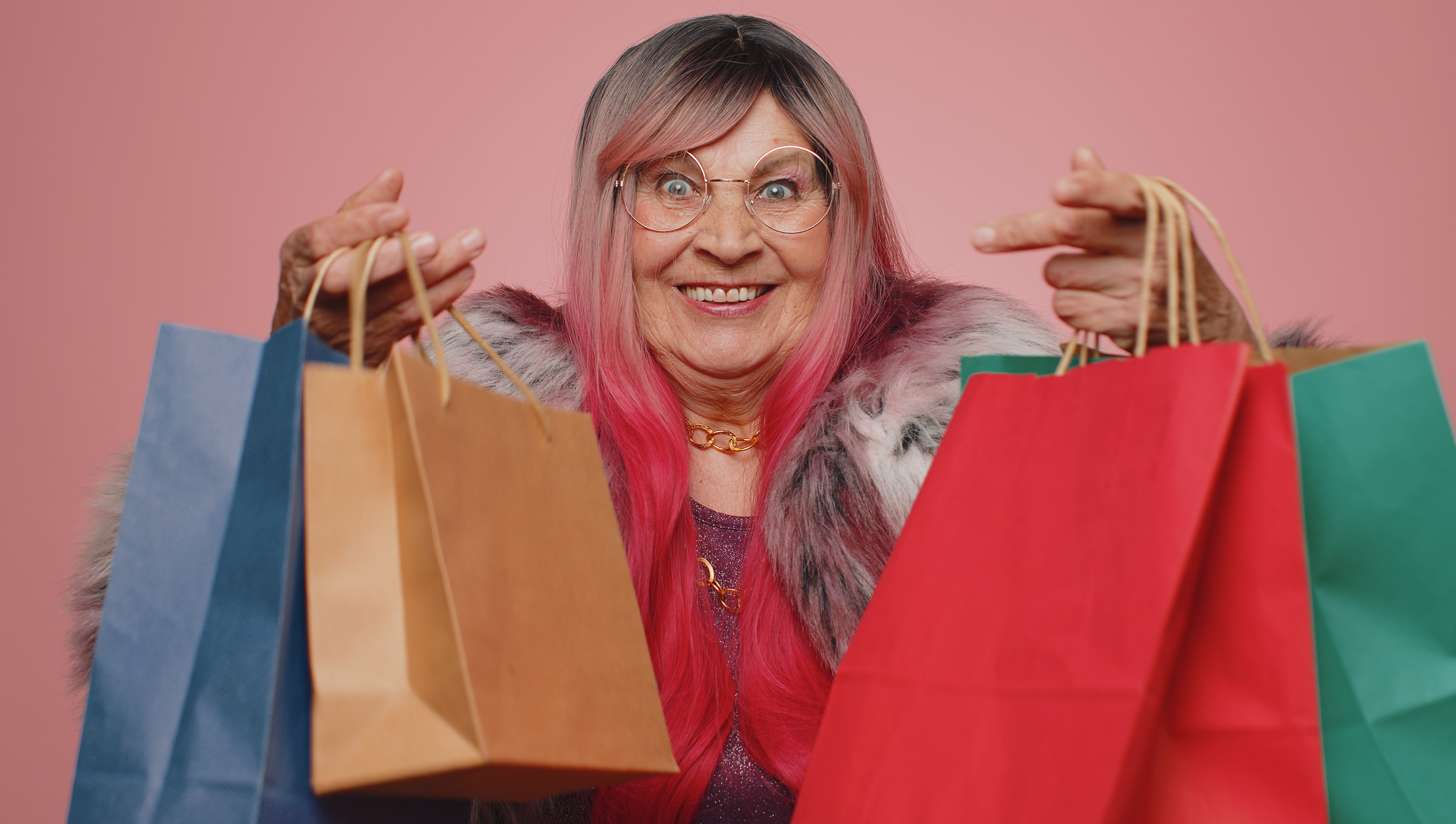 Una anciana sonríe mientras sostiene bolsas de la compra | Foto: Shutterstock