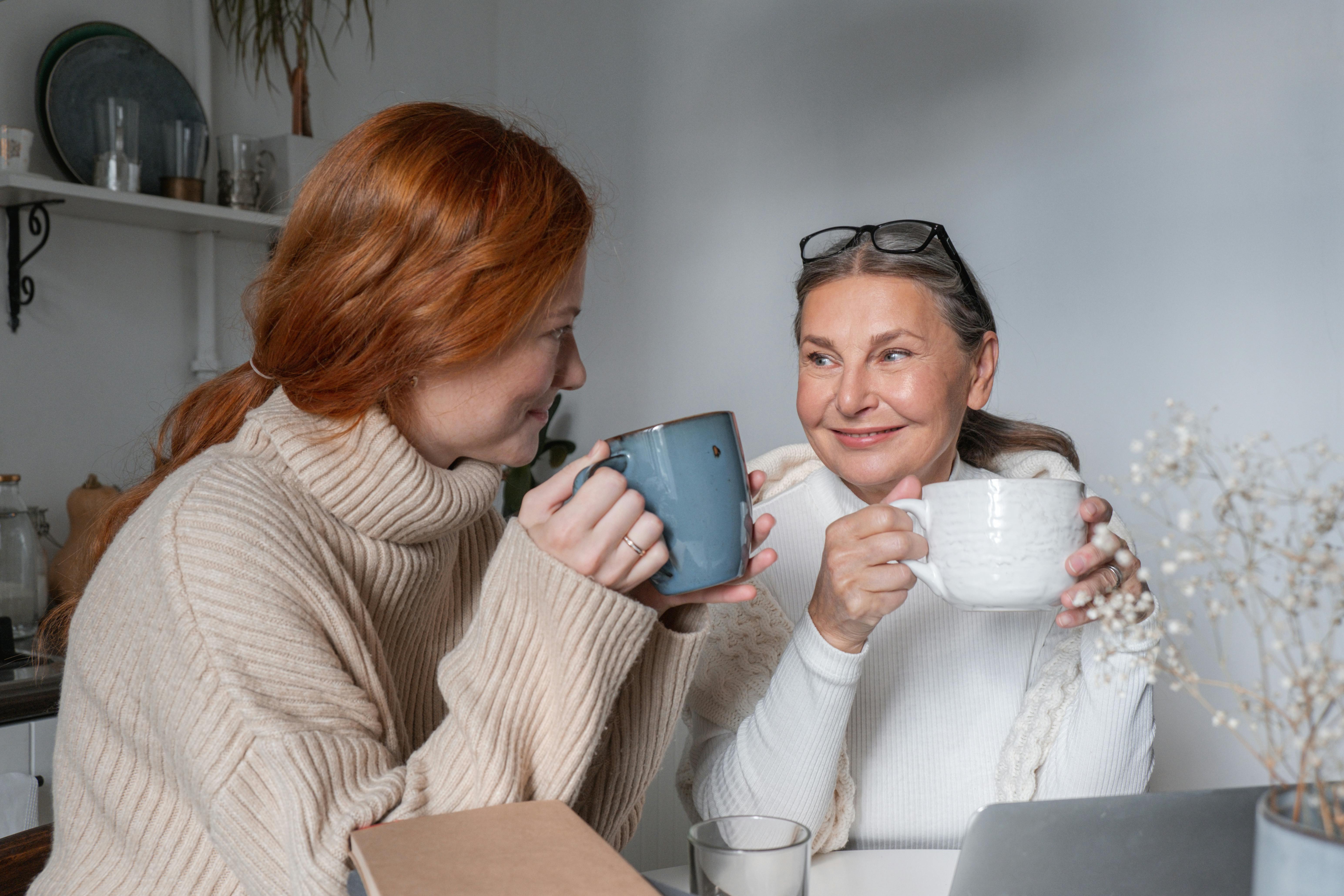 Una mujer mayor y otra más joven sonriendo mientras toman una bebida juntas | Fuente: Pexels