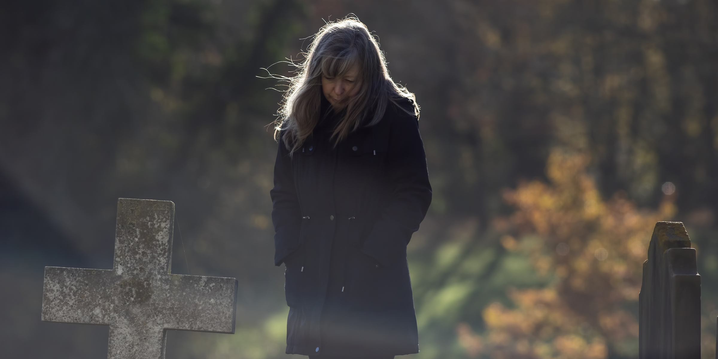 Una mujer afligida cerca de una lápida ⏐ Fuente: Shutterstock