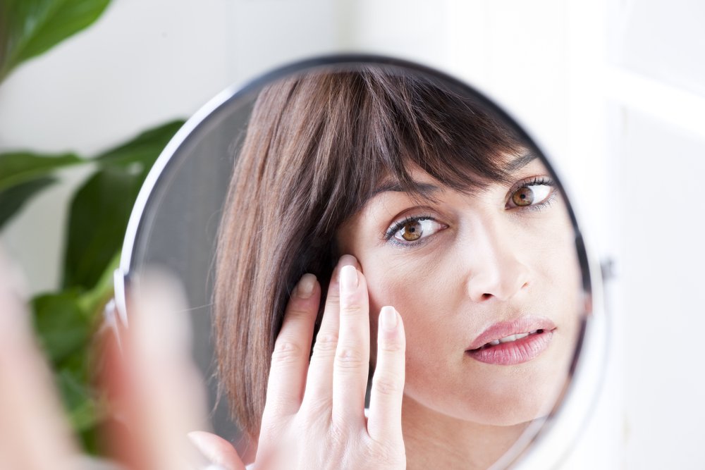 Mujer mirándose a sí misma en el espejo. | Foto: Shutterstock
