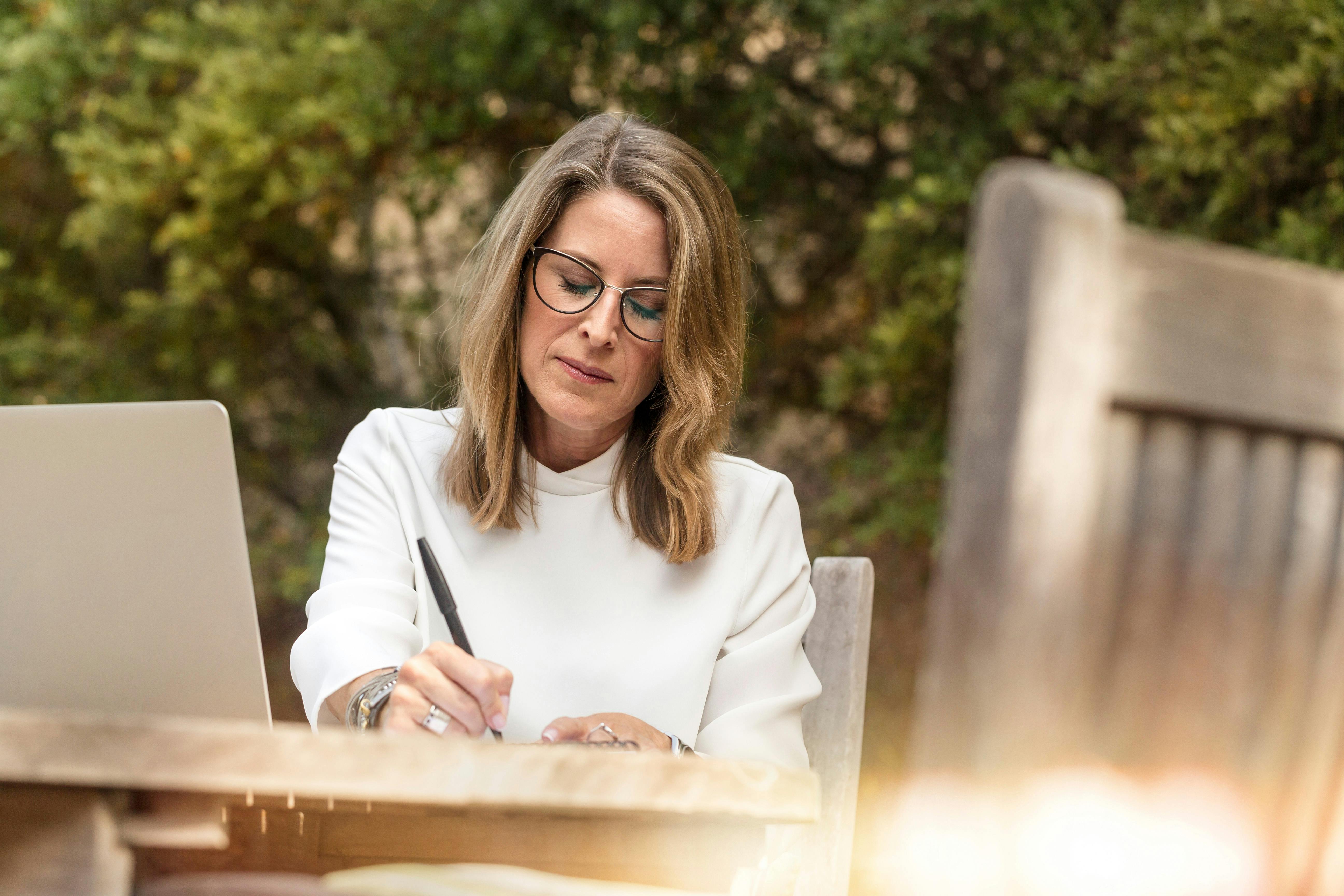 Una mujer escribiendo en la mesa de su jardín | Fuente: Pexels