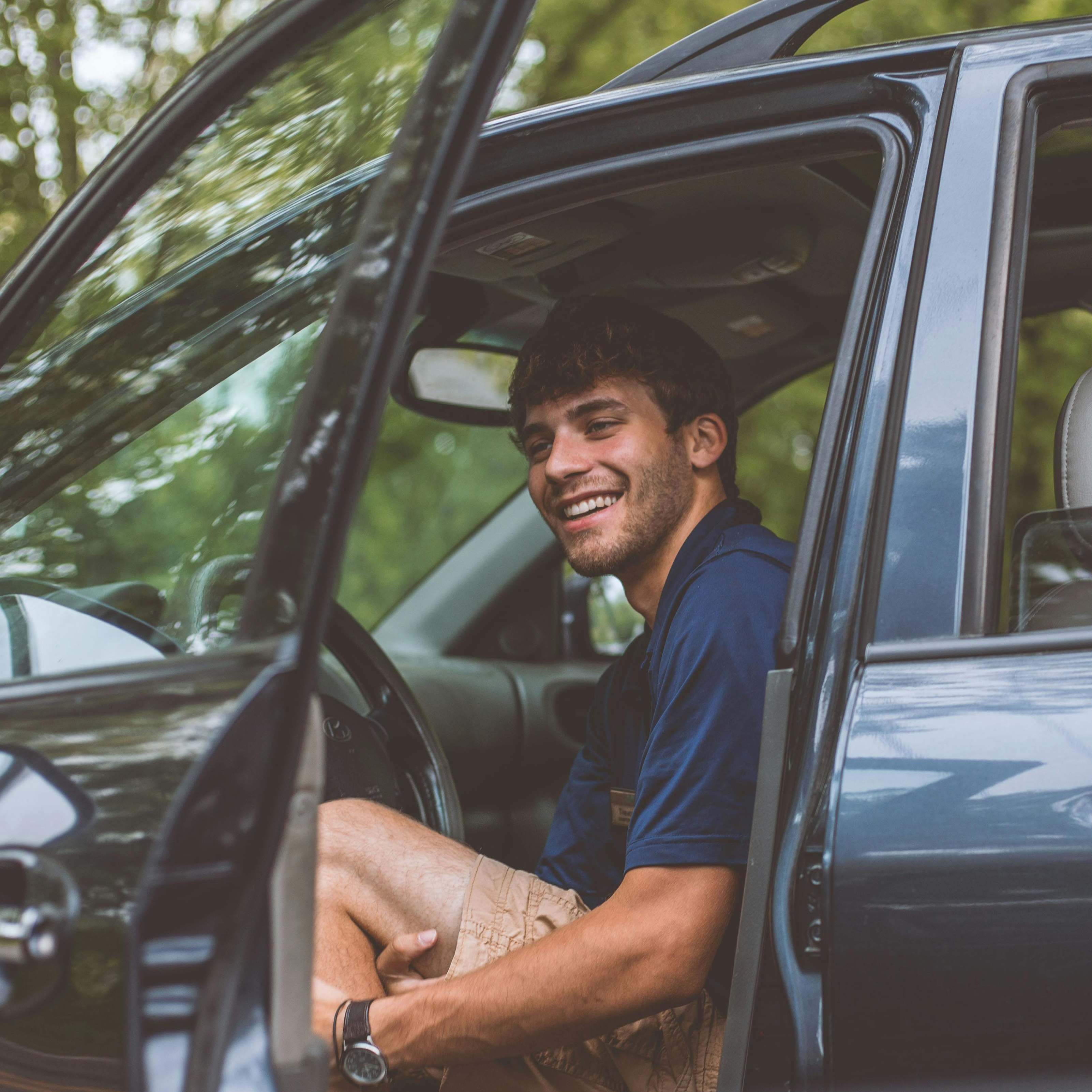 Un hombre abriendo la puerta del conductor de un Automóvil, sonriendo | Fuente: Pexels