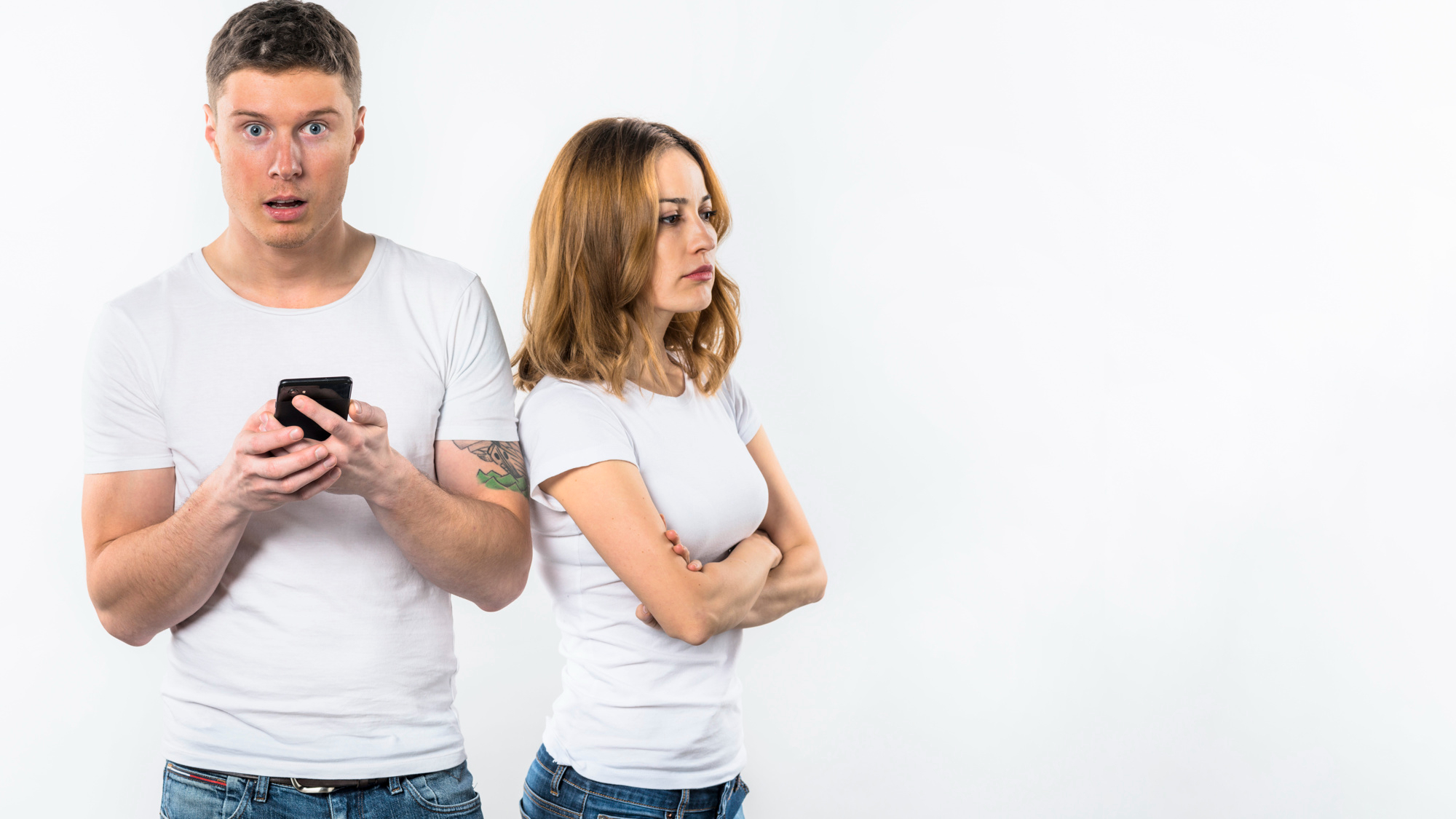 Un hombre reacciona sorprendido a algo en un teléfono mientras su novia parece disgustada | Fuente: Freepik
