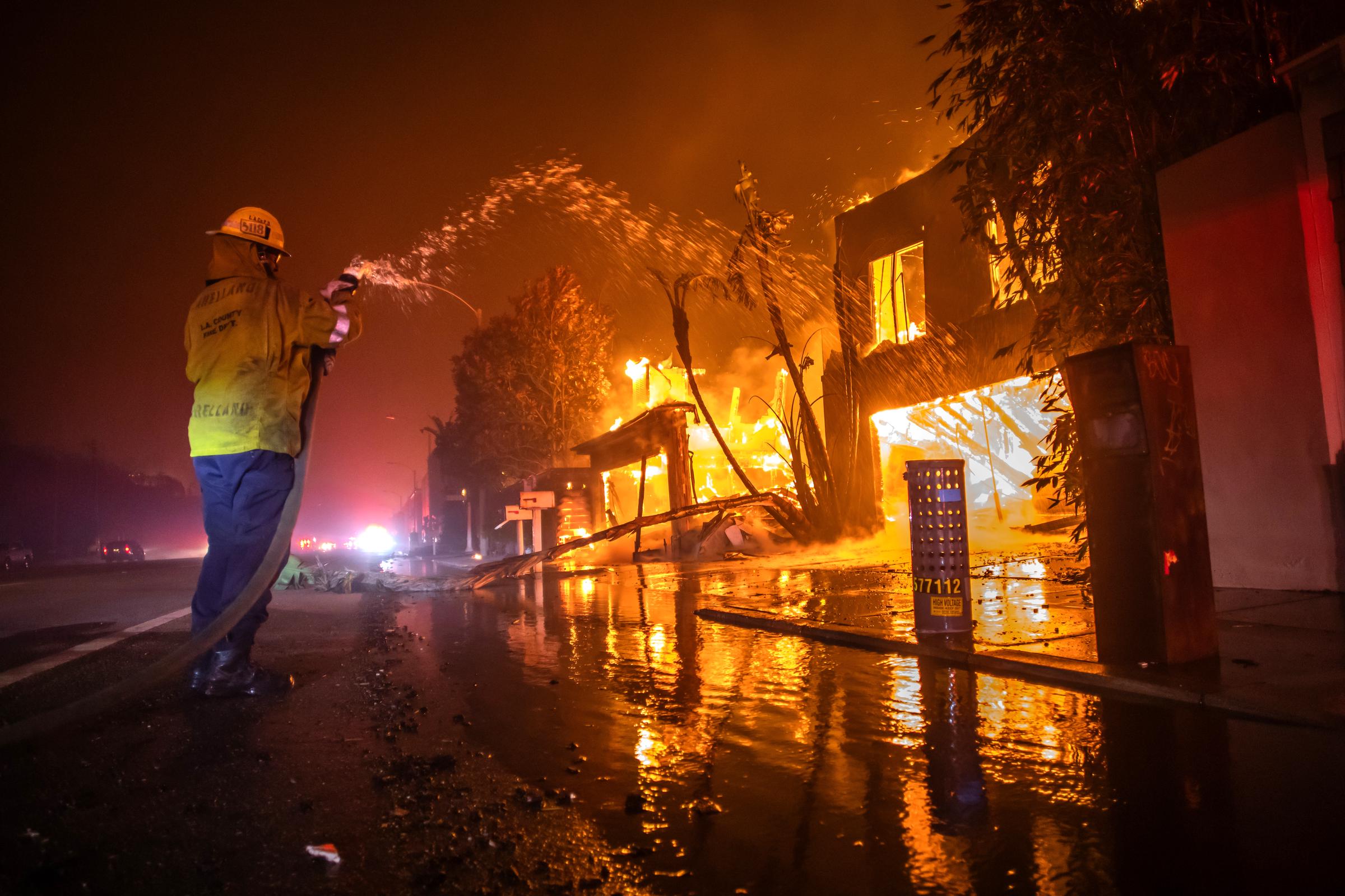 Un bombero lucha contra el incendio de Palisades mientras quema casas en la autopista de la Costa del Pacífico en medio de una fuerte tormenta de viento en Los Ángeles, California, el 8 de enero de 2025 | Fuente: Getty Images