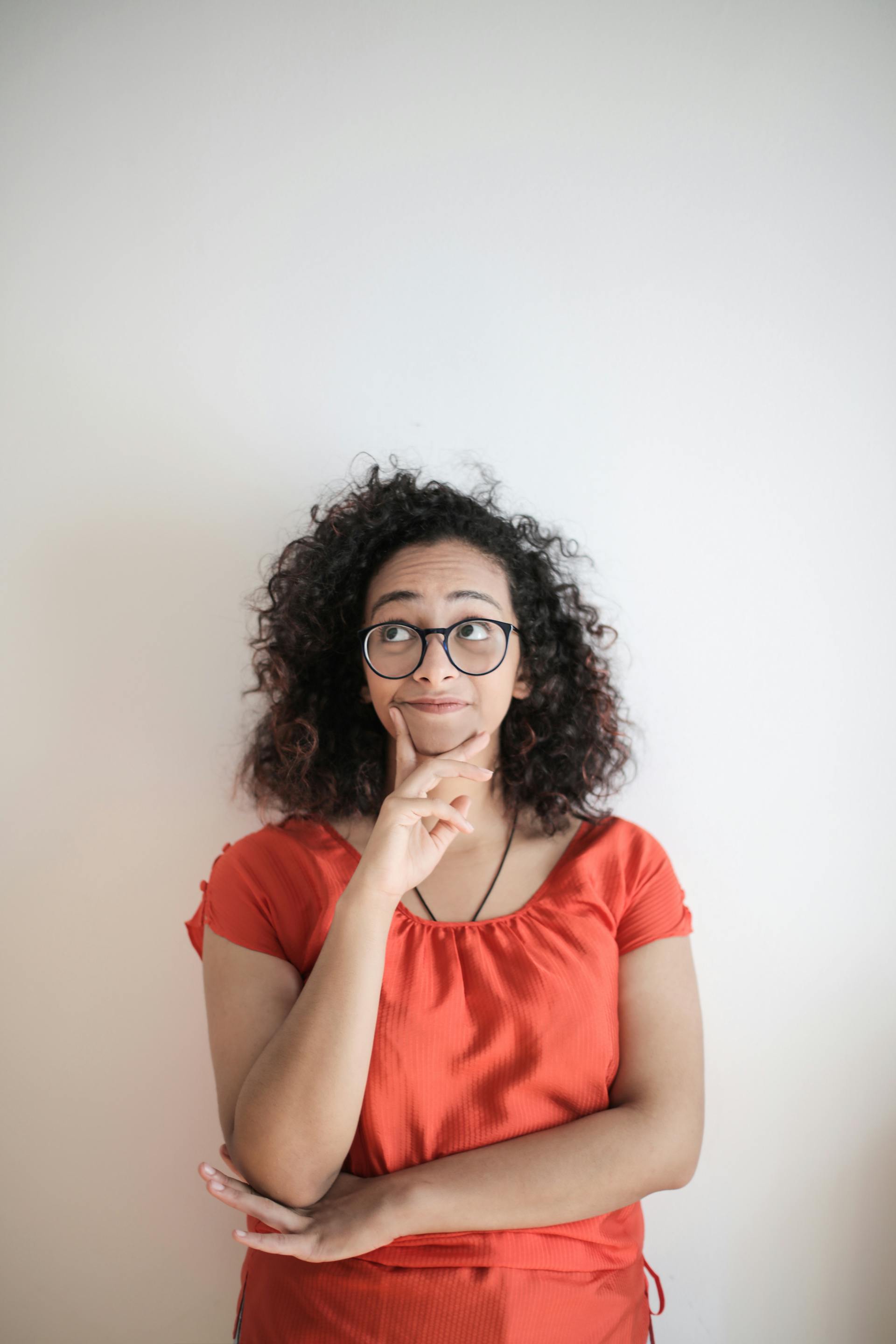 Una mujer de pie contra una pared, pensando | Fuente: Pexels