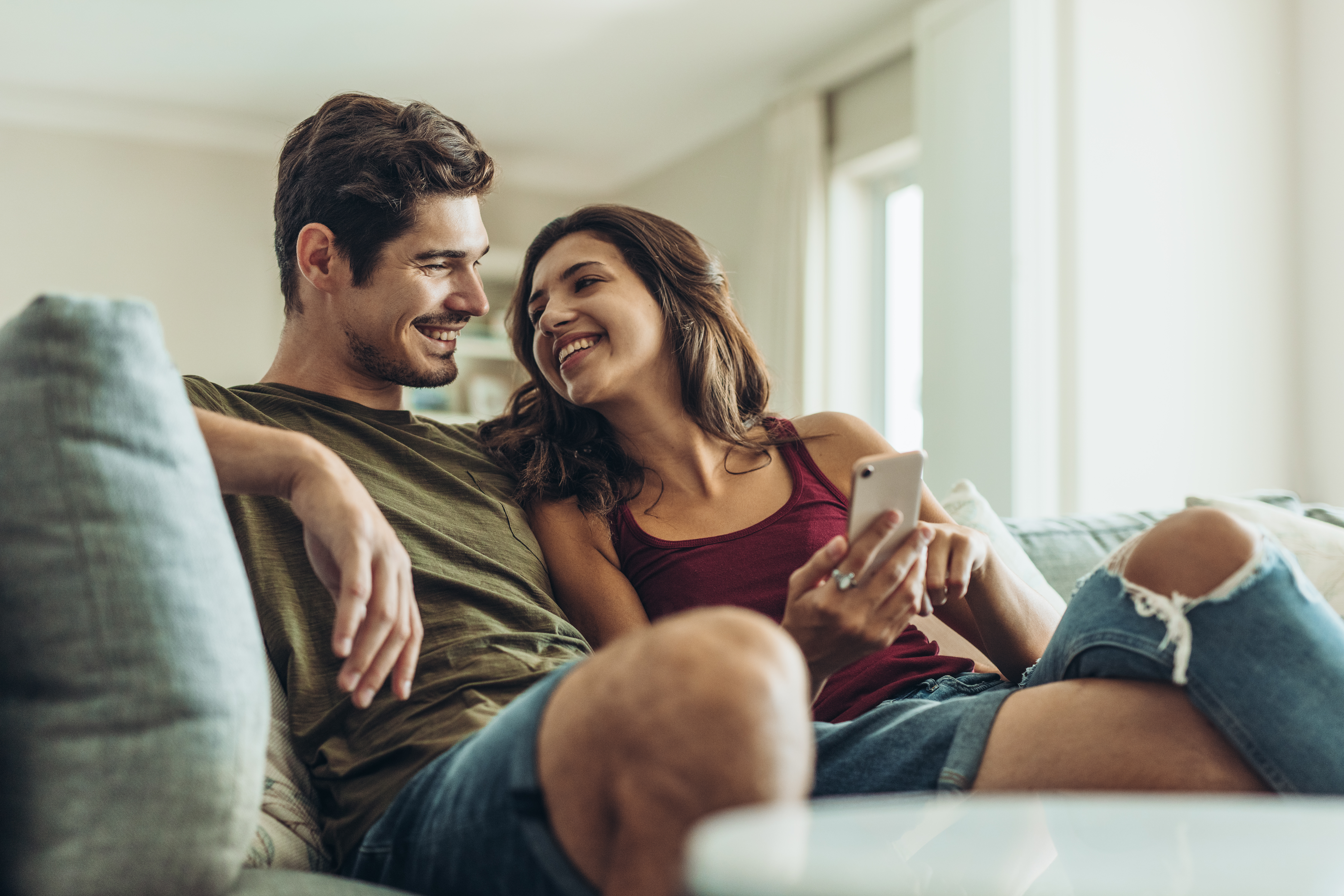 Una pareja feliz sonriéndose en el sofá | Foto: Shutterstock