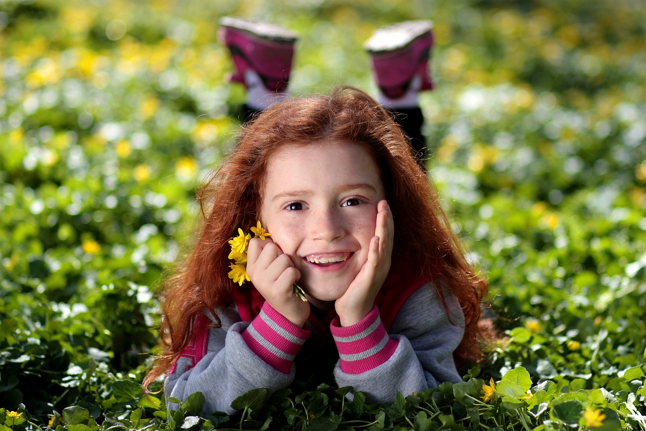 Una chica pelirroja sonriente sosteniendo flores | Fuente: Pixabay