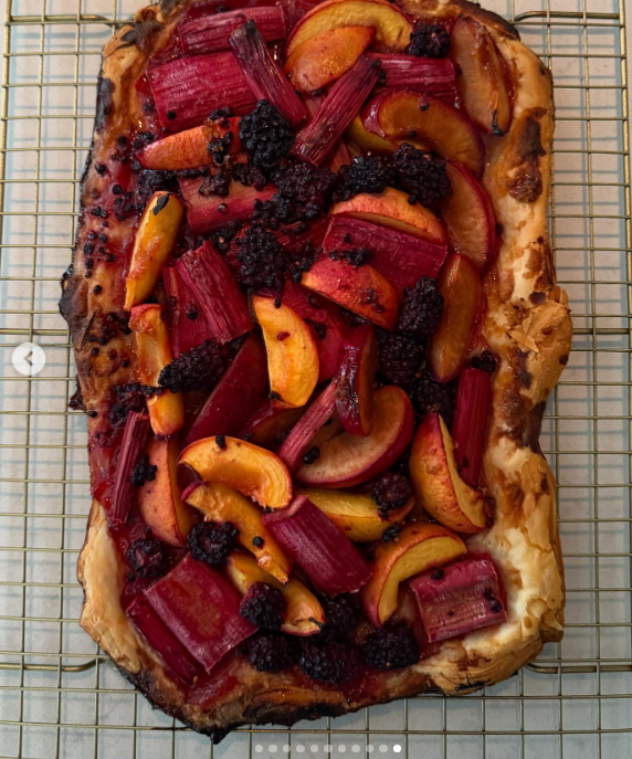 Una tarta rústica de frutas se enfría en Arcady, coronada con ruibarbo asado, frutas de hueso cortadas en rodajas y bayas oscuras cultivadas directamente en los terrenos de la finca. Este dulce artesanal, que refleja las pasiones culinarias de Pamela Anderson y su estilo de vida centrado en las plantas, convierte las cosechas de temporada del huerto en arte comestible. Compartió esta deliciosa creación junto con un pie de foto reflexivo: "Pienso en la vida como un jardín… Puedes volver a plantar, empezar de nuevo y hacerla tuya. 🤍 Con cariño, P". | Fuente: Instagram/pamelaanderson