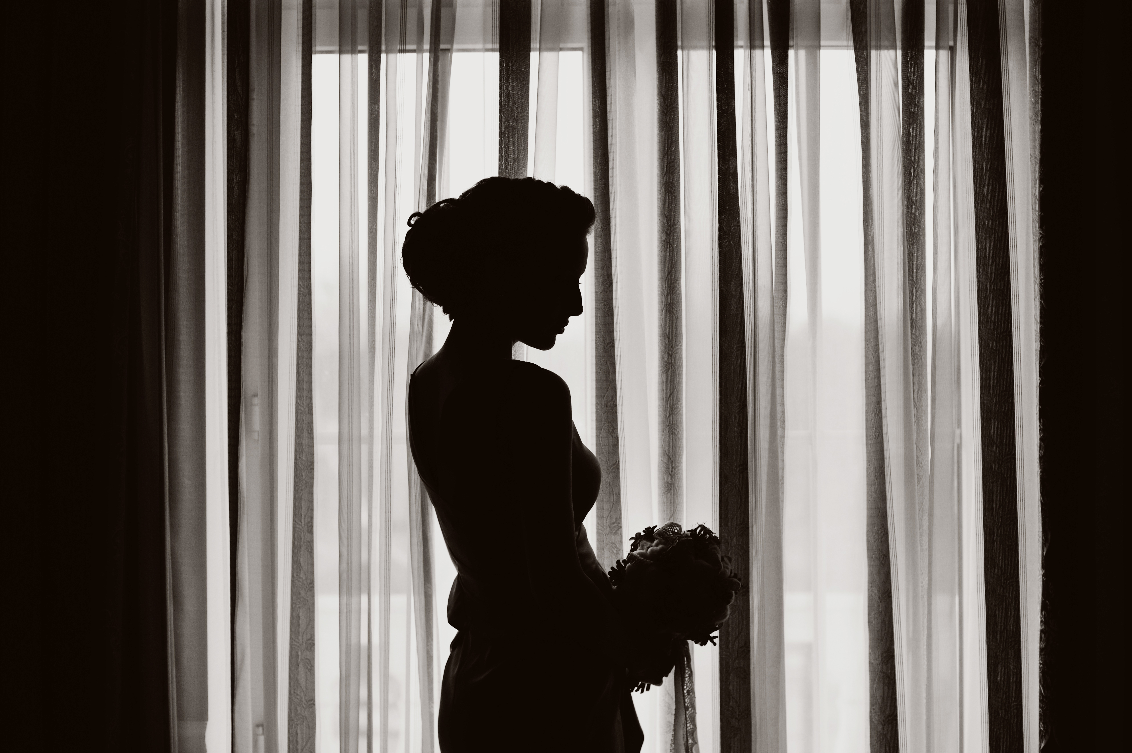 Silueta de una mujer de pie cerca de una ventana | Fuente: Shutterstock