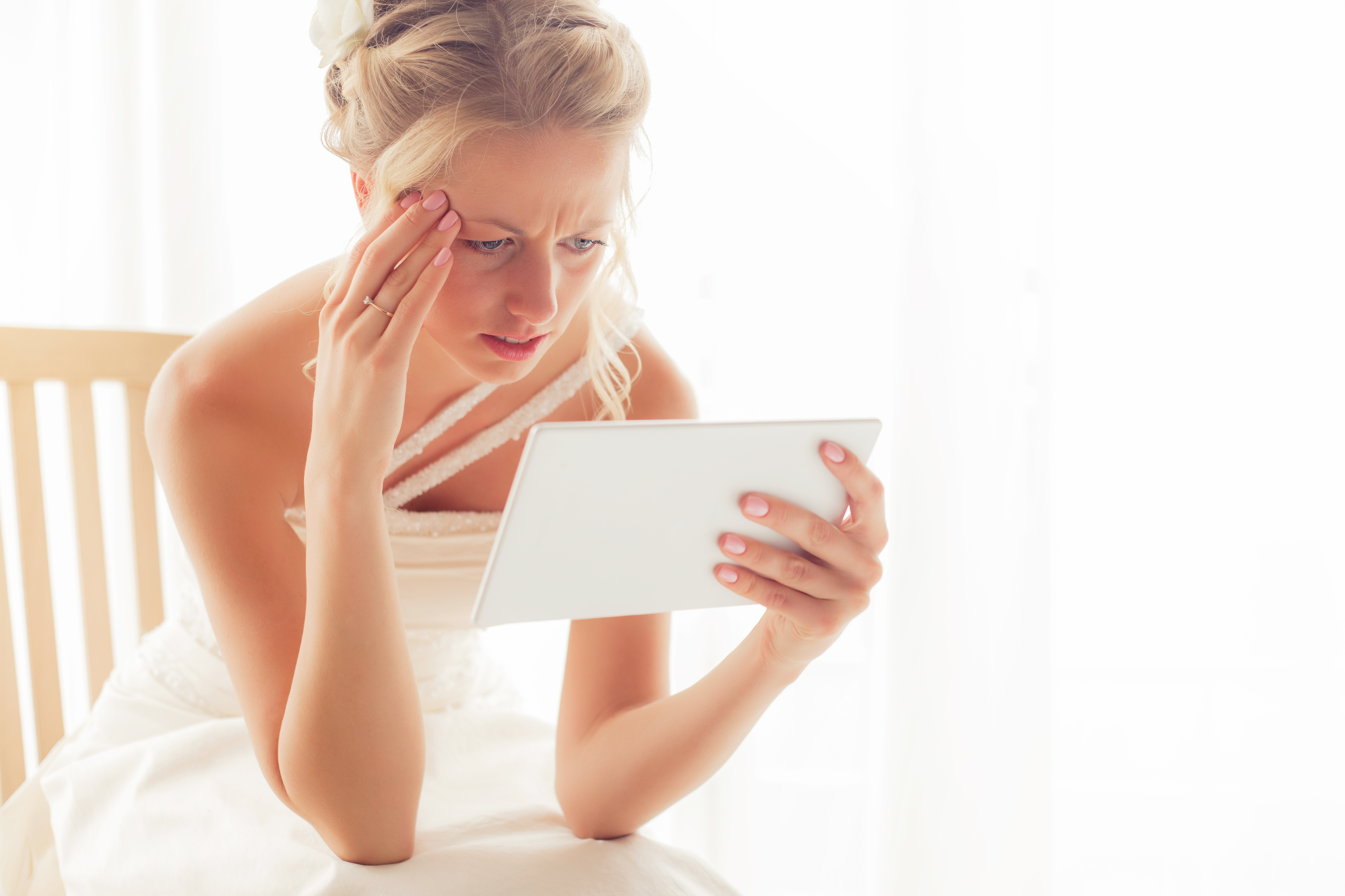 Una novia preocupada mirando una tableta | Fuente: Shutterstock