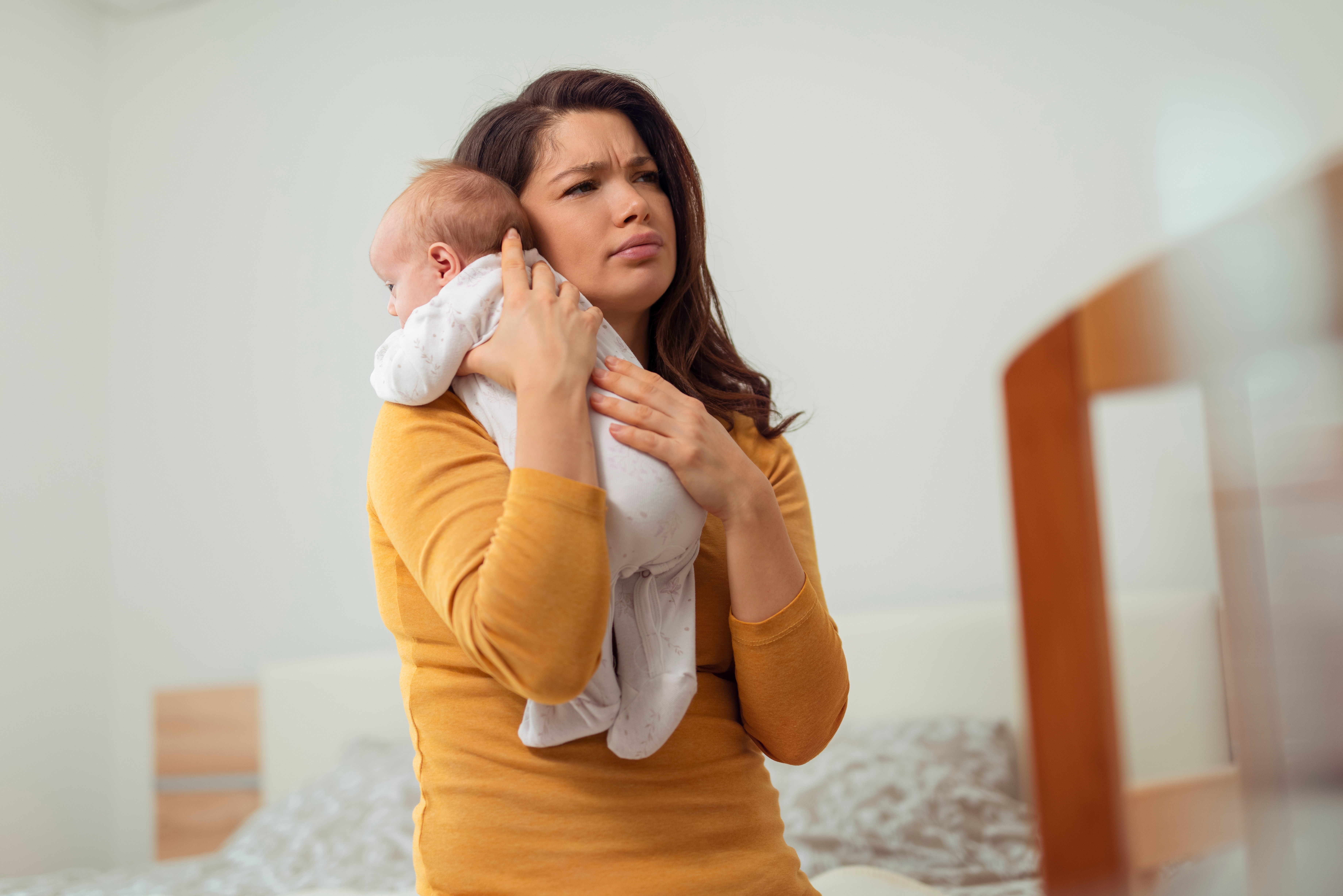 Una mujer con aspecto cansado mientras sostiene a un bebé | Fuente: Shutterstock