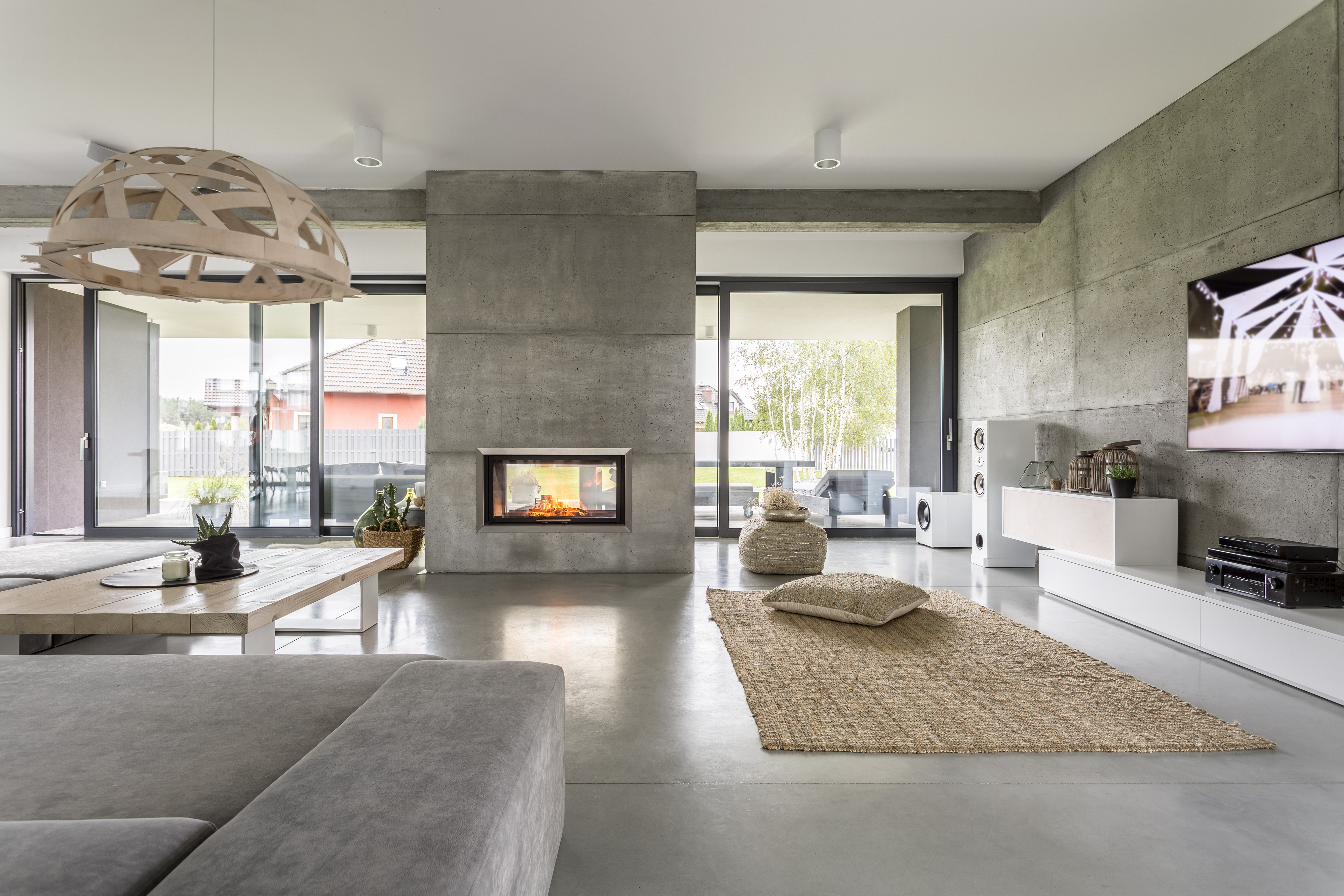 Interior de chalet espacioso con efecto de pared de cemento, chimenea y tv.| Fuente: Shutterstock