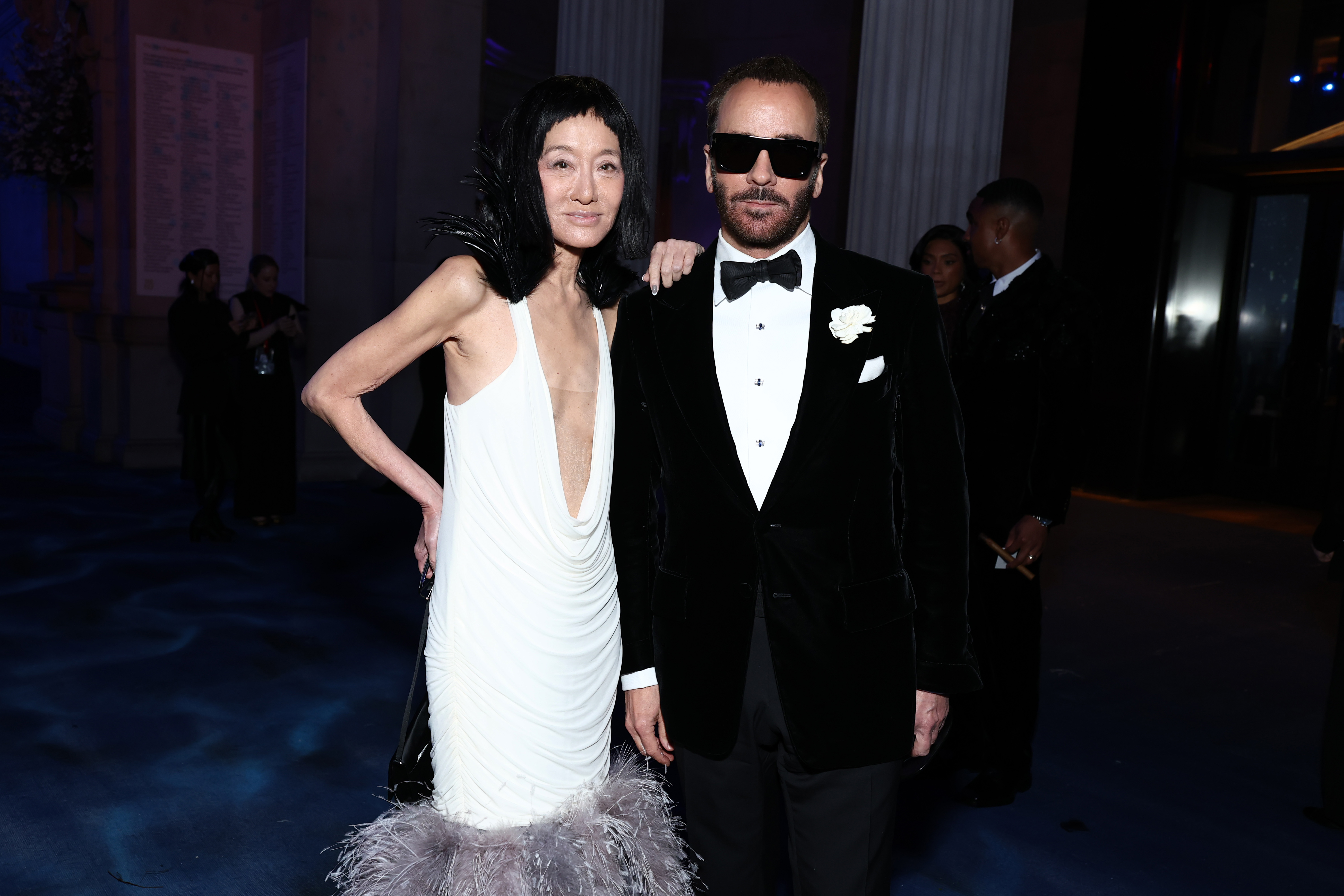Vera Wang junto al diseñador Tom Ford, ambos vestidos con conjuntos en blanco y negro que hacen un guiño al glamour atemporal durante la reunión nocturna de alto nivel.
