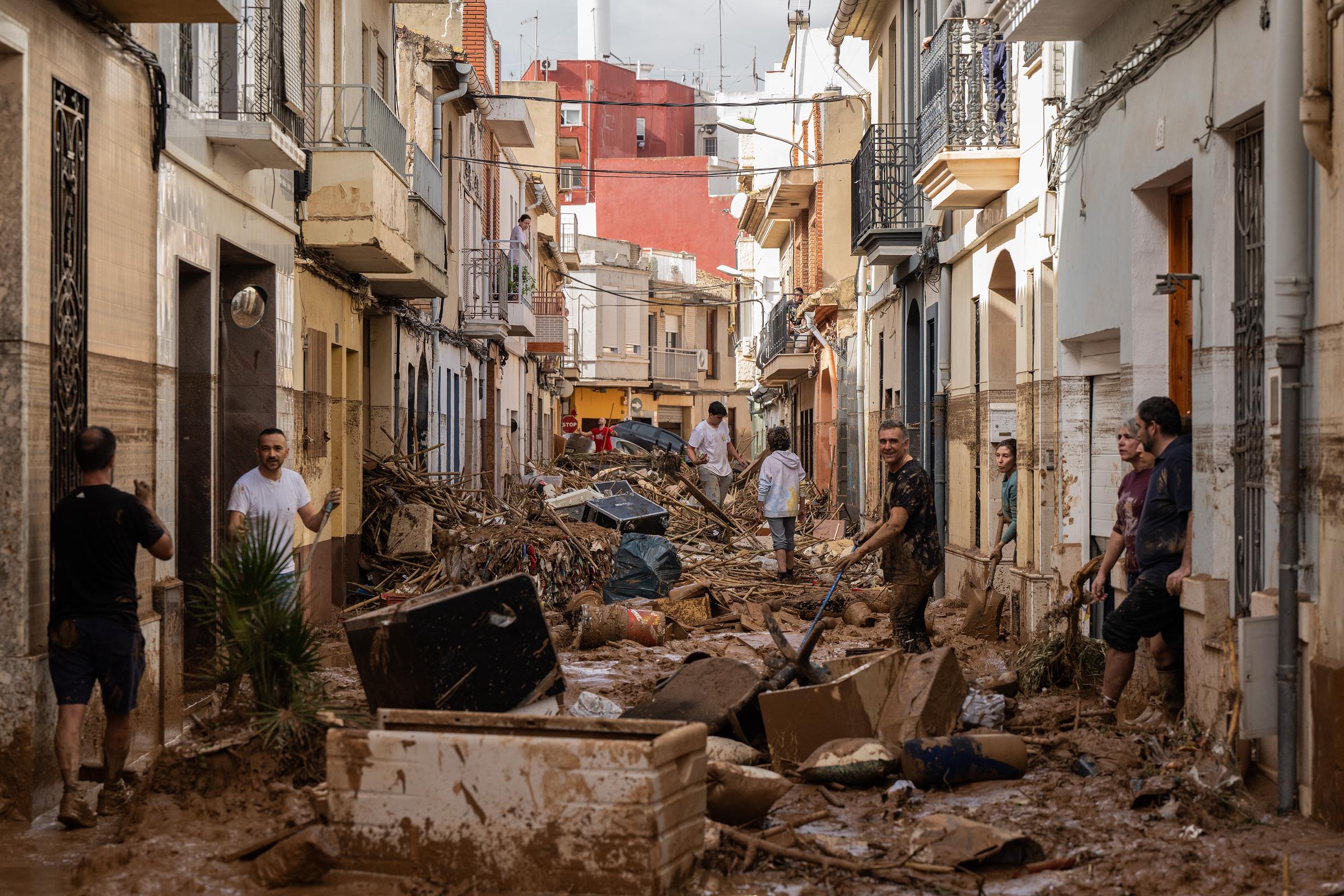 Residentes limpian una calle cubierta de barro y escombros después de que las inundaciones afectaran a gran parte del país el 31 de octubre de 2024 en el municipio valenciano de Paiporta | Fuente: Getty Images