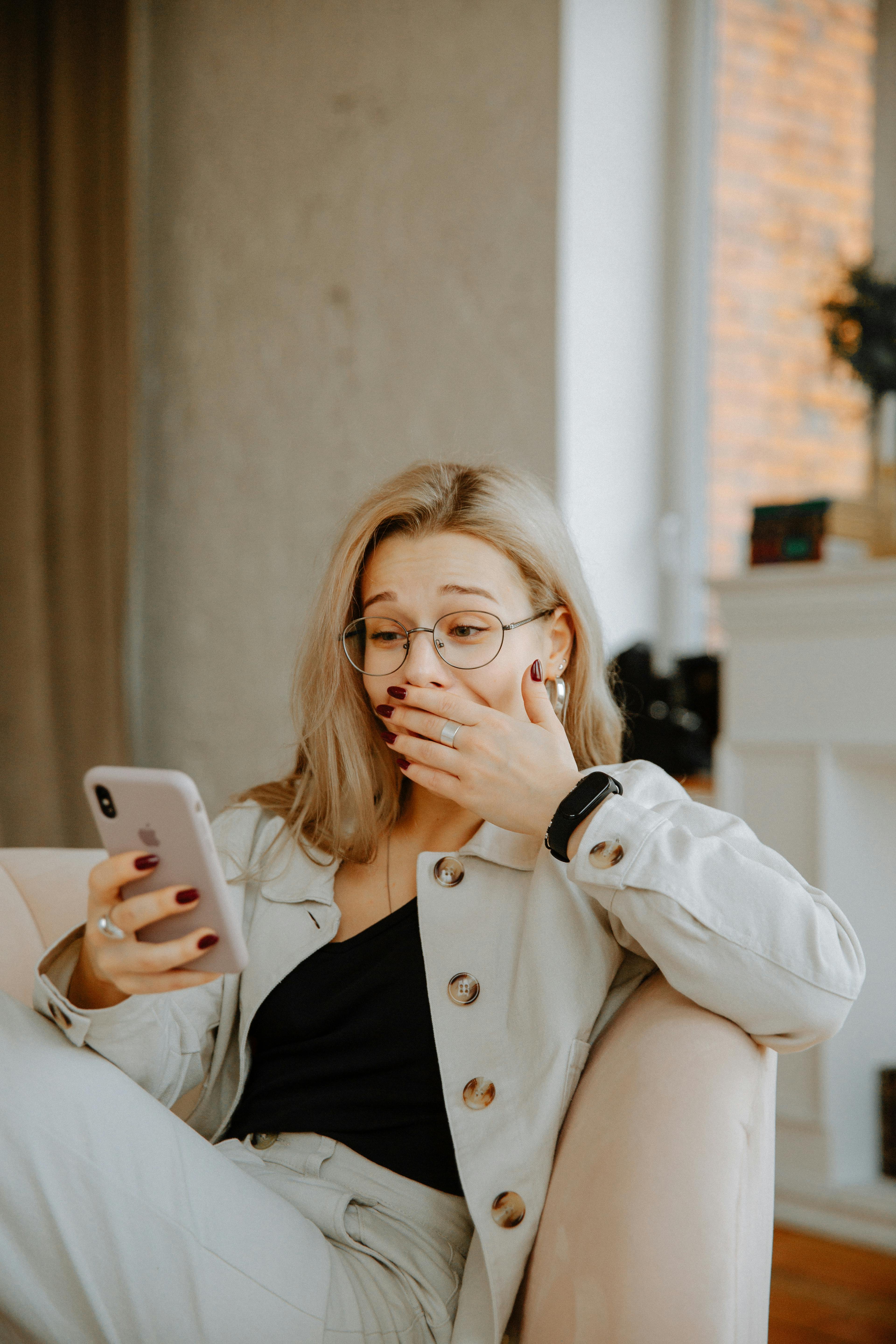 Una mujer se tapa la cara mientras mira su teléfono | Fuente: Pexels