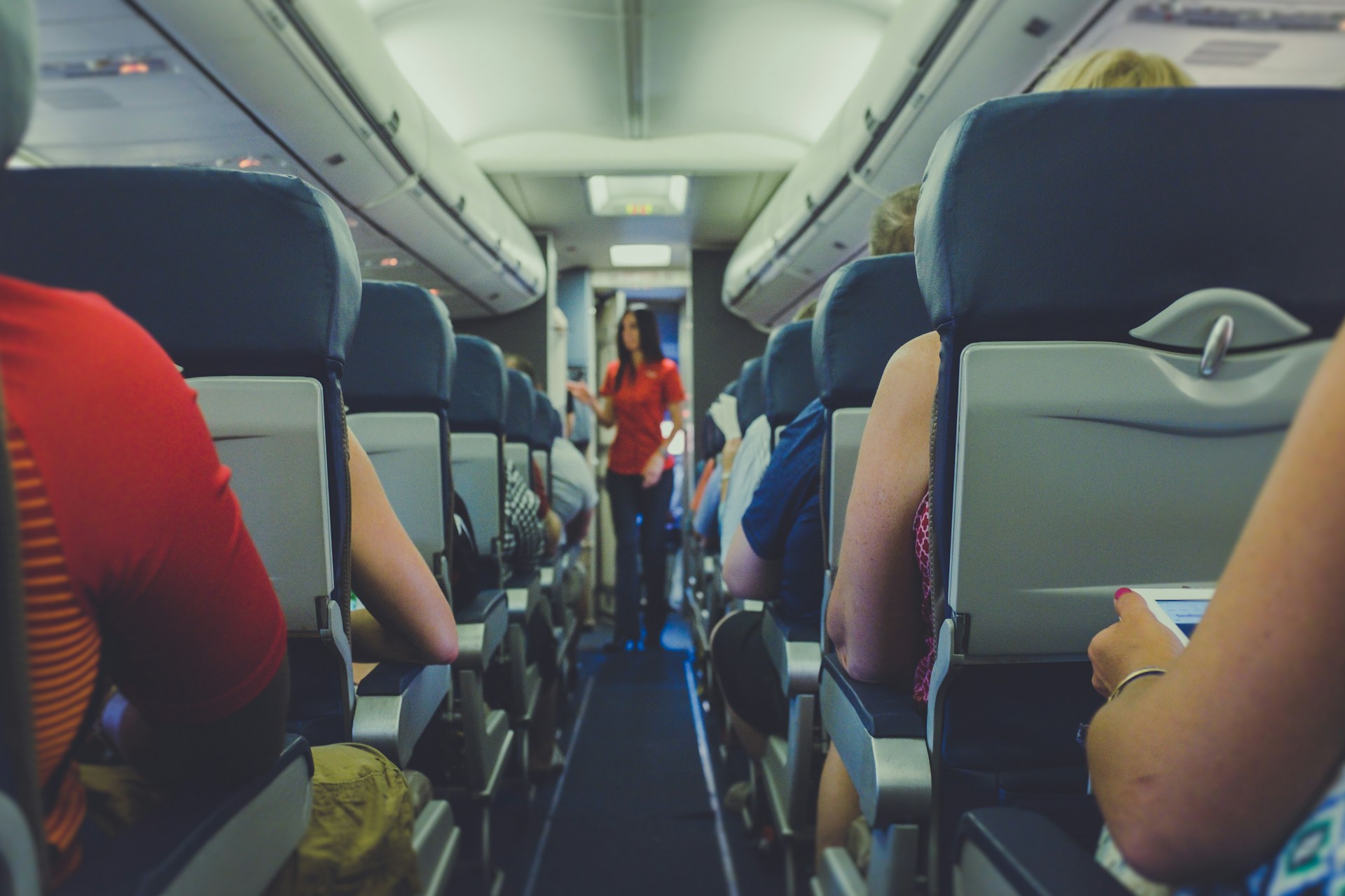 Una azafata examinando los problemas de los pasajeros en el pasillo de clase turista | Fuente: Unsplash