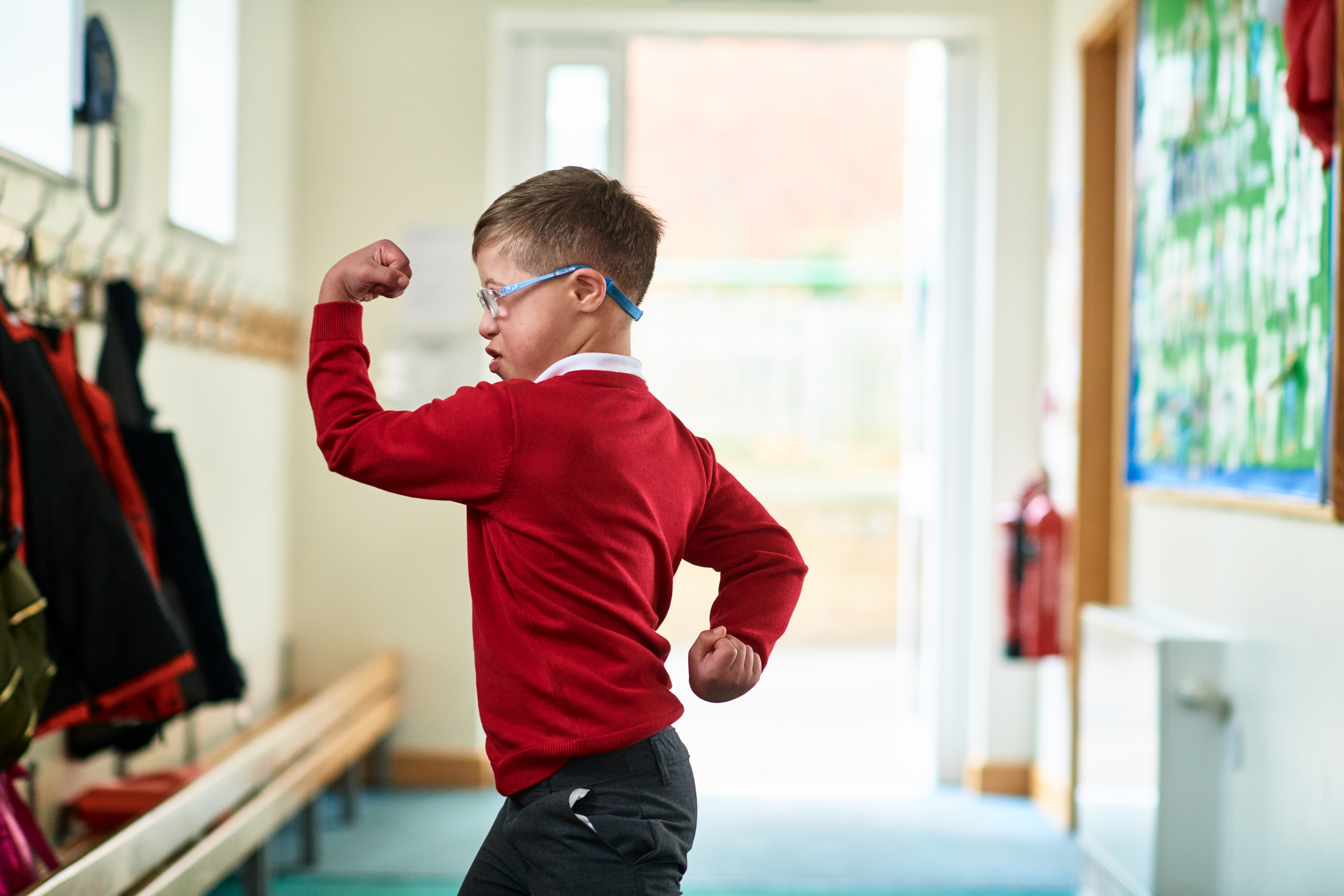 Niño con síndrome de Down flexionando los músculos | Foto: Getty Images