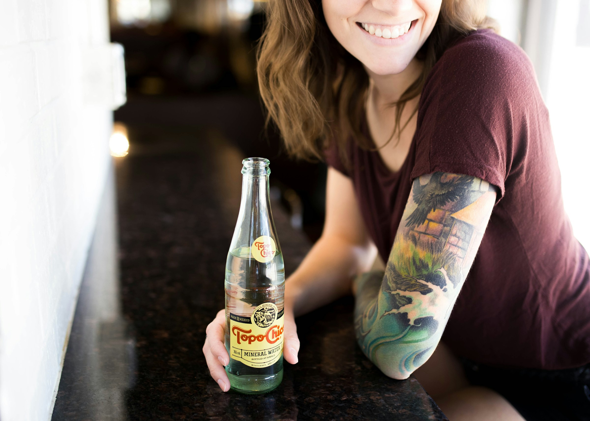 Una mujer con un tatuaje sujetando una botella | Fuente: Unsplash