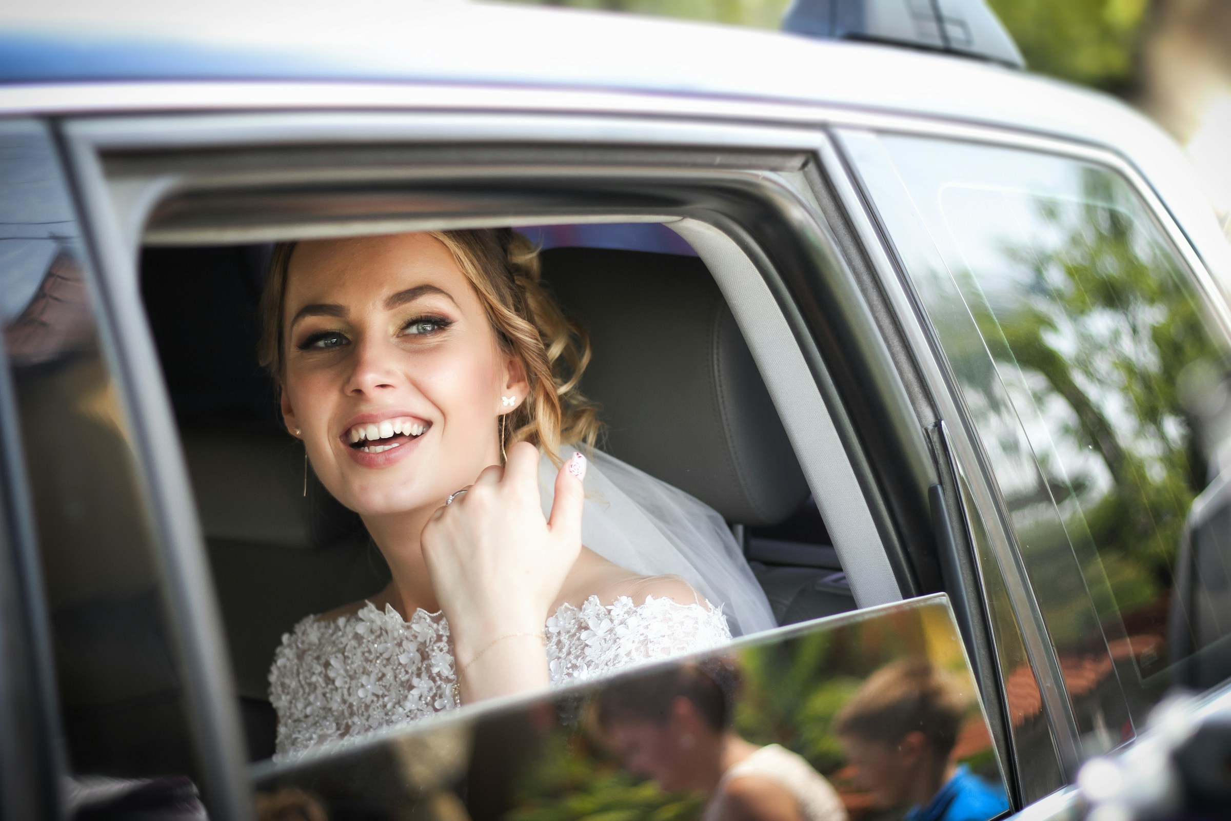 Una novia en un Automóvil mirando al exterior y sonriendo | Fuente: Unsplash