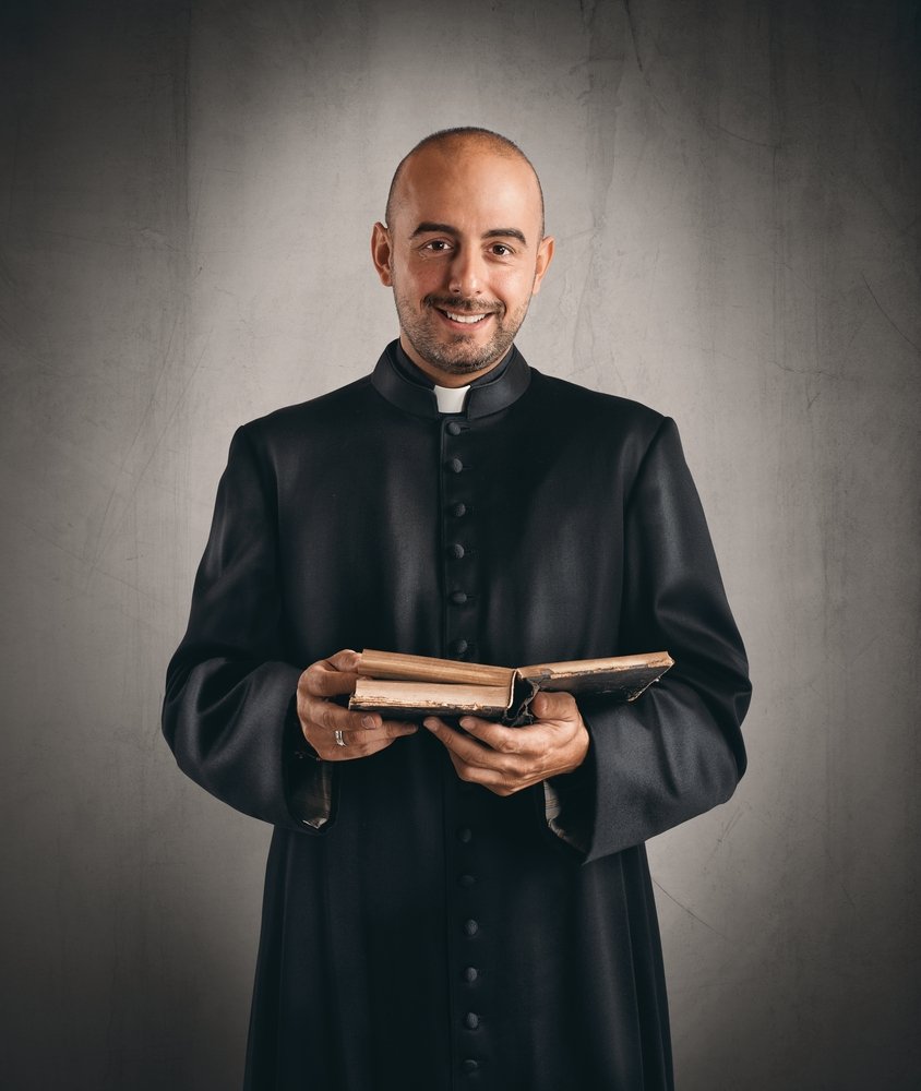 Pastor de una iglesia con un libro en las manos, sonrie. | Foto: Pexels